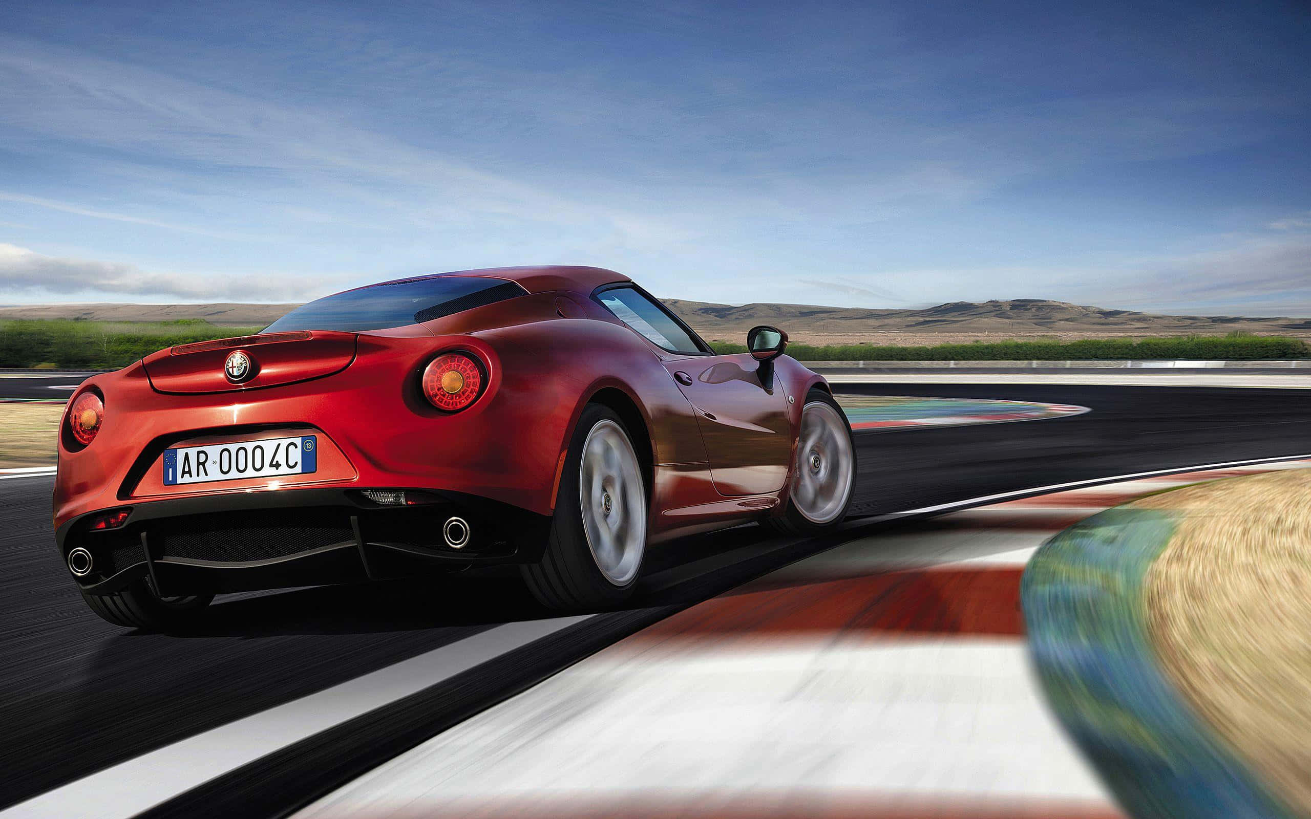 Alfa Romeo 4c 桌布 壁紙 — 一輛充滿活力的紅色Alfa Romeo 4C跑車在晴朗的藍天下繞著賽道彎道飛馳。