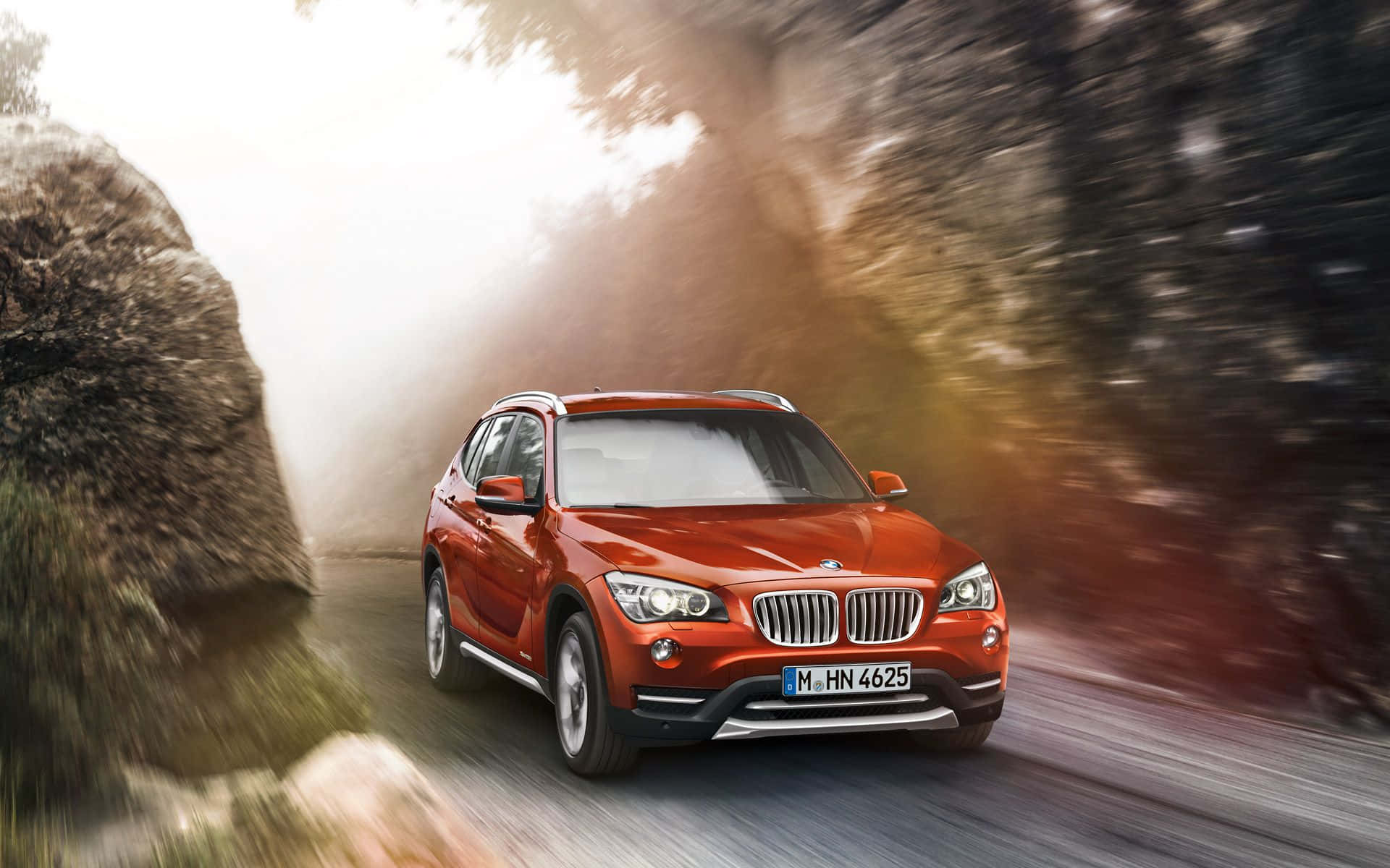 Bmw I8 桌布 壁紙 — 一輛充滿活力的紅色BMW X1 SUV在森林道路上疾馳，帶有動態模糊和陽光照射的樹木。