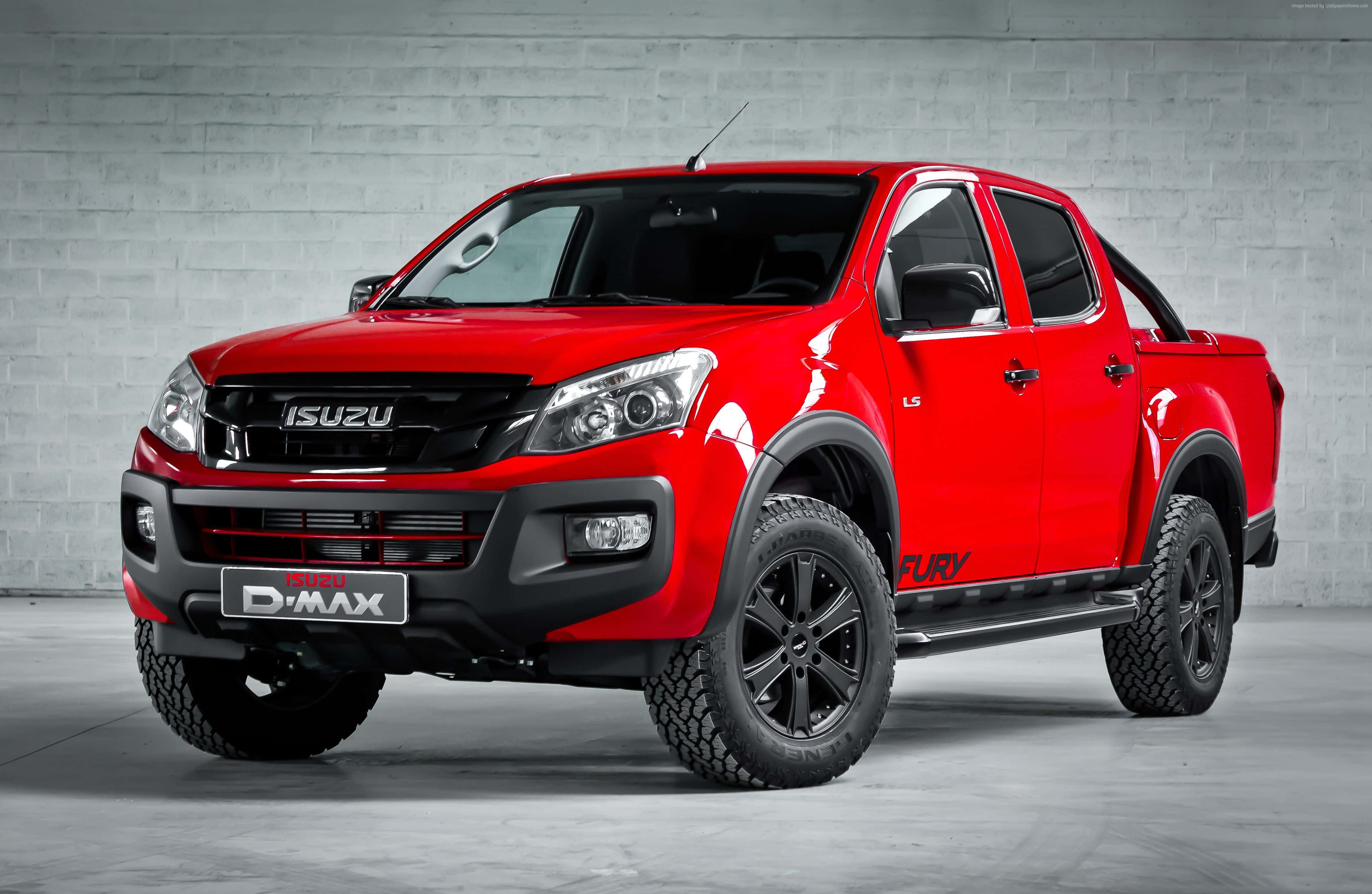 Isuzu 桌布 壁紙 — 一輛充滿活力的紅色Isuzu D-Max皮卡車，帶有黑色飾件和堅固輪胎，在簡約的灰色磚牆前蓄勢待發。
