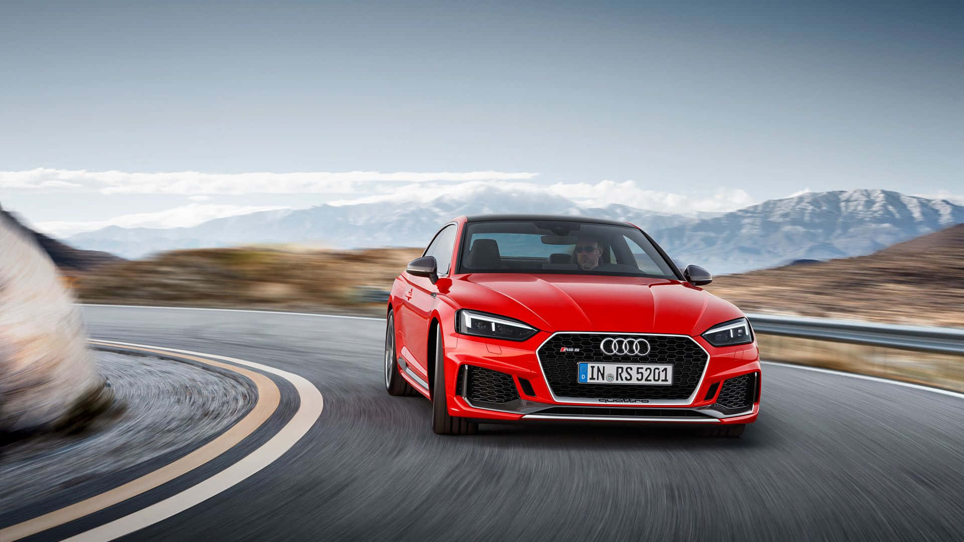 Audi S5 桌布 壁紙 — 一輛充滿活力的紅色奧迪RS5 Coupe在蜿蜒的山路上疾馳，背景是白雪覆蓋的山峰。
