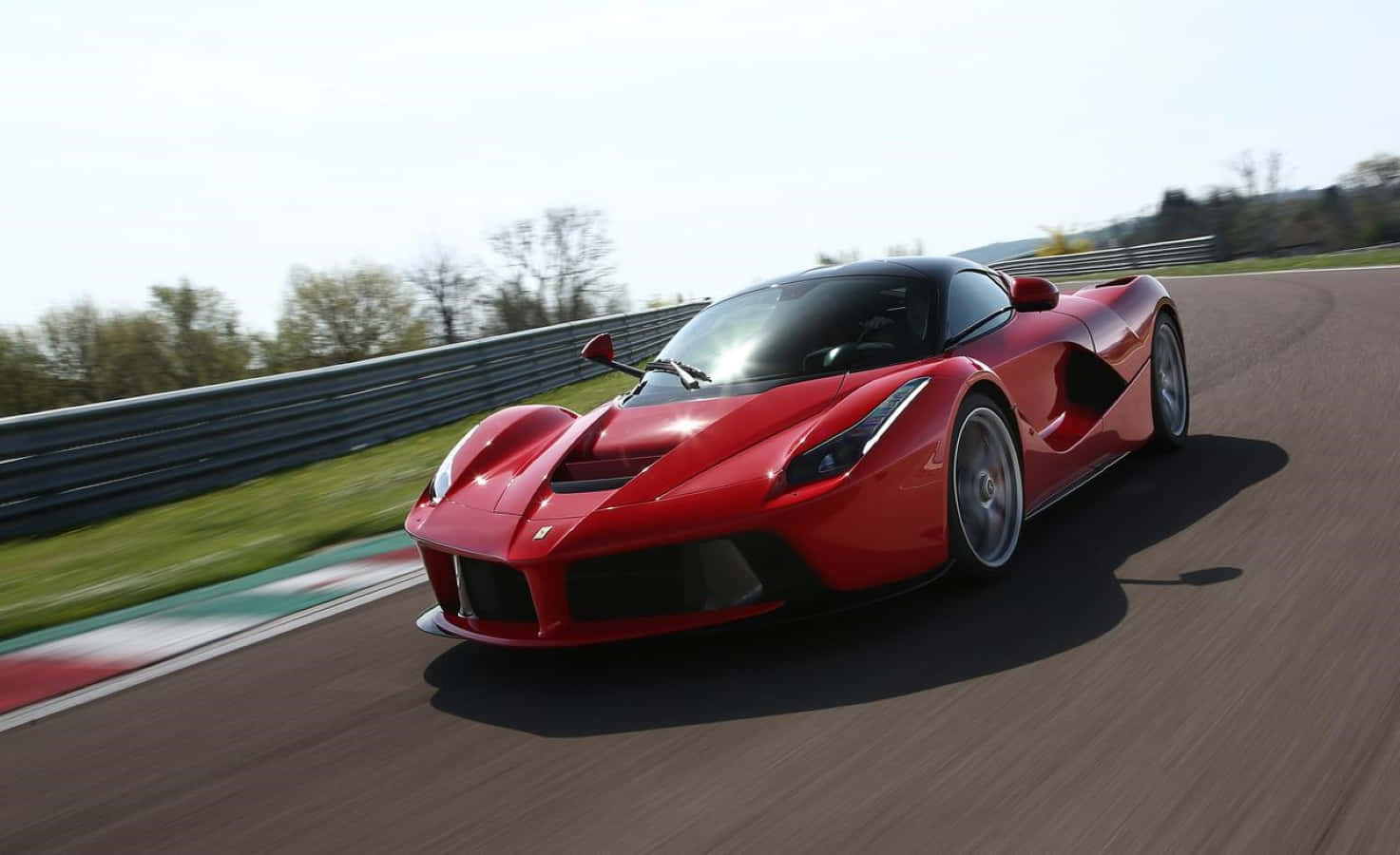 Ferrari Laferrari 桌布 壁紙 — 一輛充滿活力的紅色法拉利 LaFerrari 在賽道上疾馳，背景有動態模糊和綠樹。