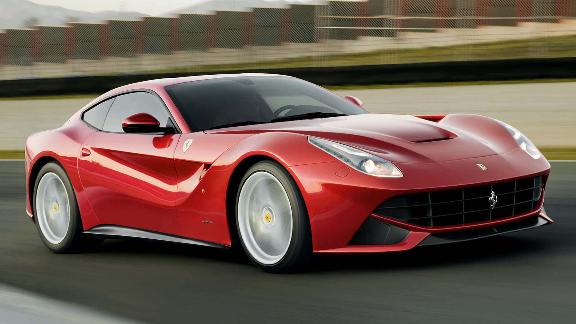 Ferrari F12 Berlinetta 桌布 壁紙 — 一輛充滿活力的紅色法拉利F12 Berlinetta在賽道上疾馳，背景呈現動態模糊效果。
