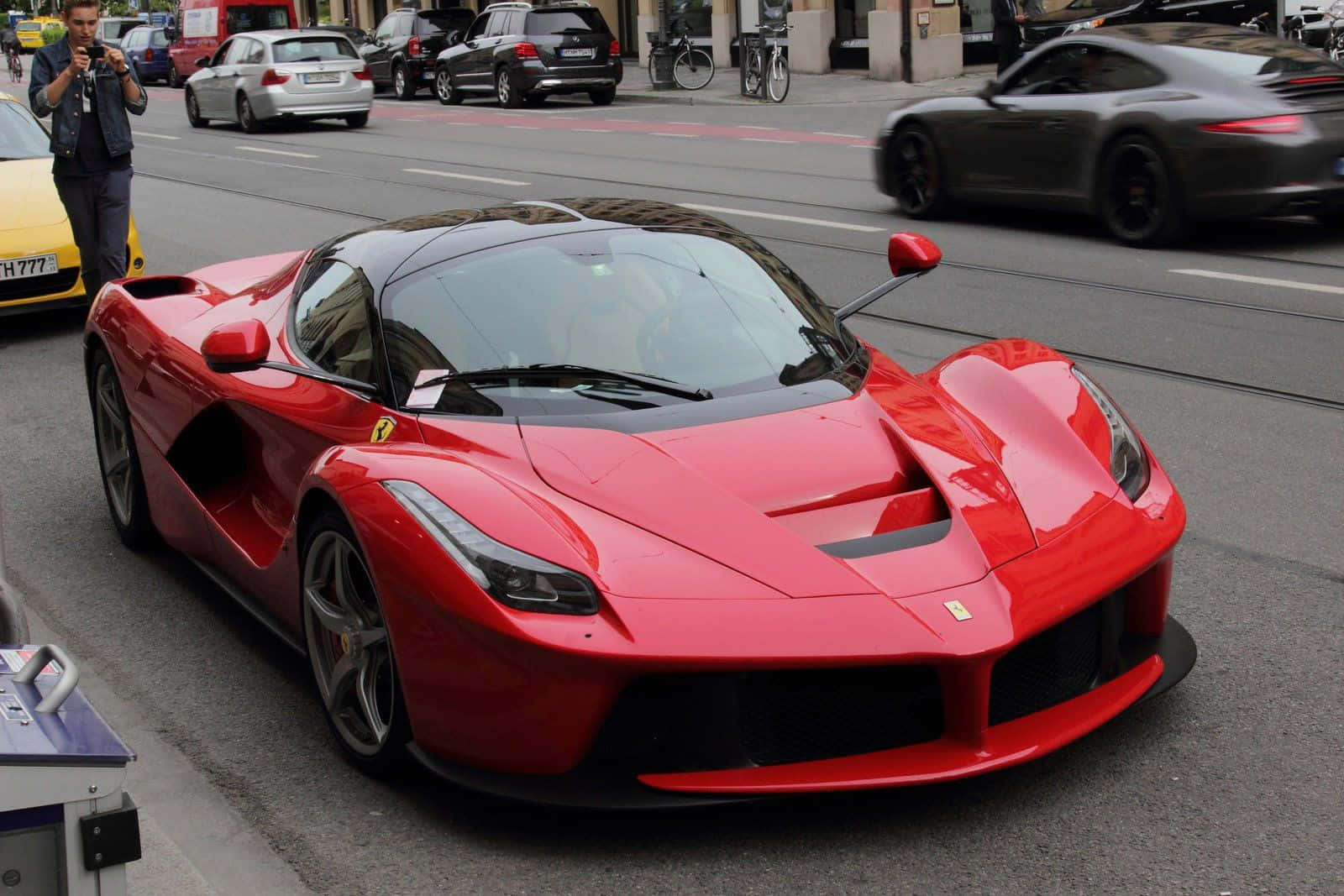 Ferrari Laferrari 桌布 壁紙 — 一輛充滿活力的紅色法拉利LaFerrari跑車停放在繁忙的城市街道上，背景有模糊的交通和一位攝影師。
