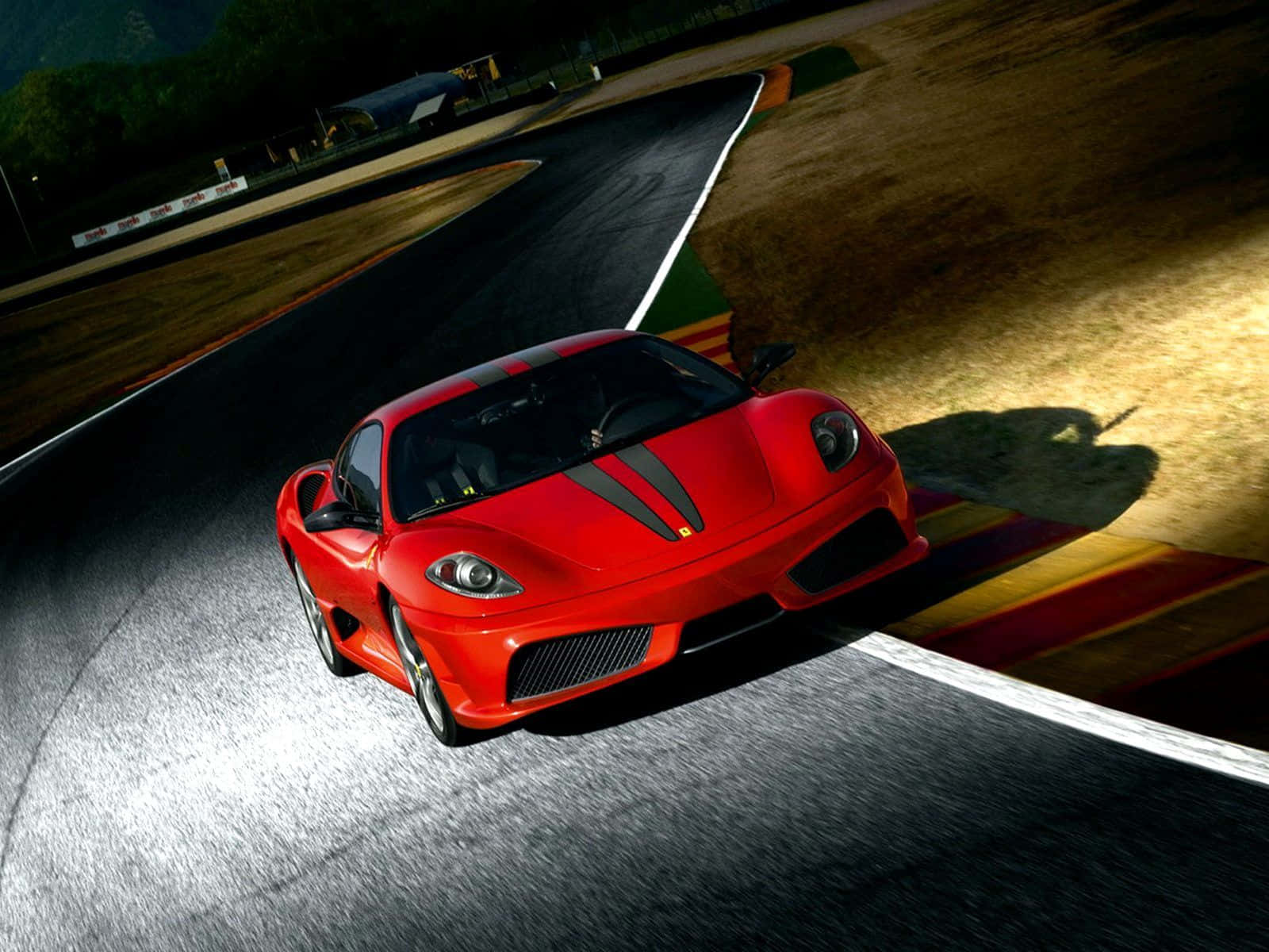 Ferrari F430 桌布 壁紙 — 一輛充滿活力的紅色法拉利跑車在戲劇性燈光下高速駛過賽車場彎道。