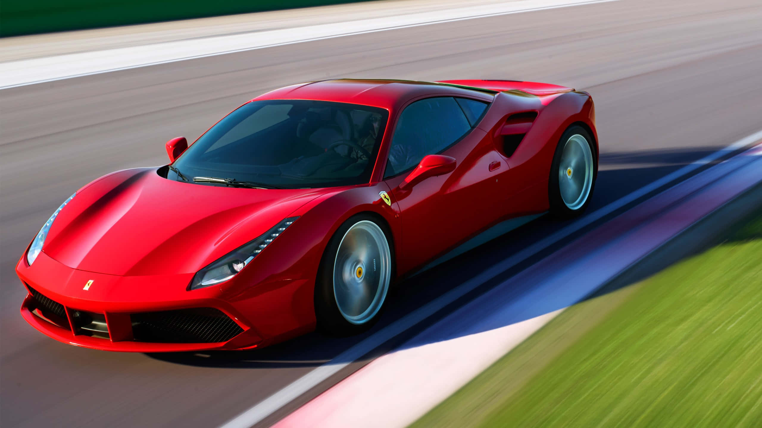 Ferrari 488 Spider 桌布 壁紙 — 一輛充滿活力的紅色法拉利跑車在明亮的日光下，沿著賽道飛馳，賽道上有模糊的綠色草地和瀝青。