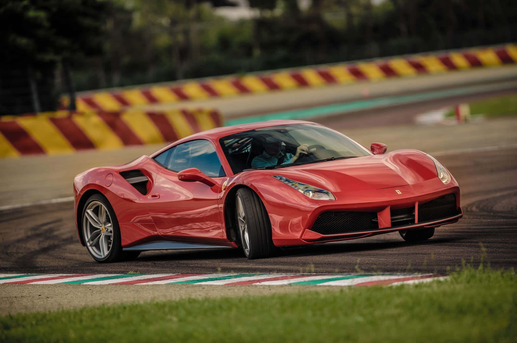 Ferrari 488 Spider 桌布 壁紙 — 一輛充滿活力的紅色法拉利跑車在賽道上疾馳，賽道兩旁是黃紅條紋的護欄和綠草。