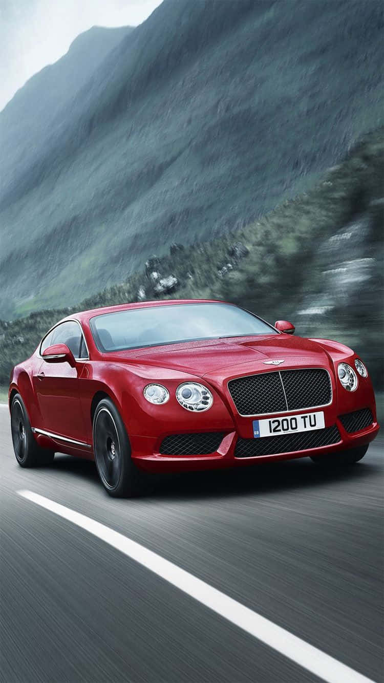 Bentley Cars 桌布 壁紙 — 一輛充滿活力的紅色賓利 Continental GT 沿著蜿蜒的山路疾馳，背景是模糊的綠色山坡。