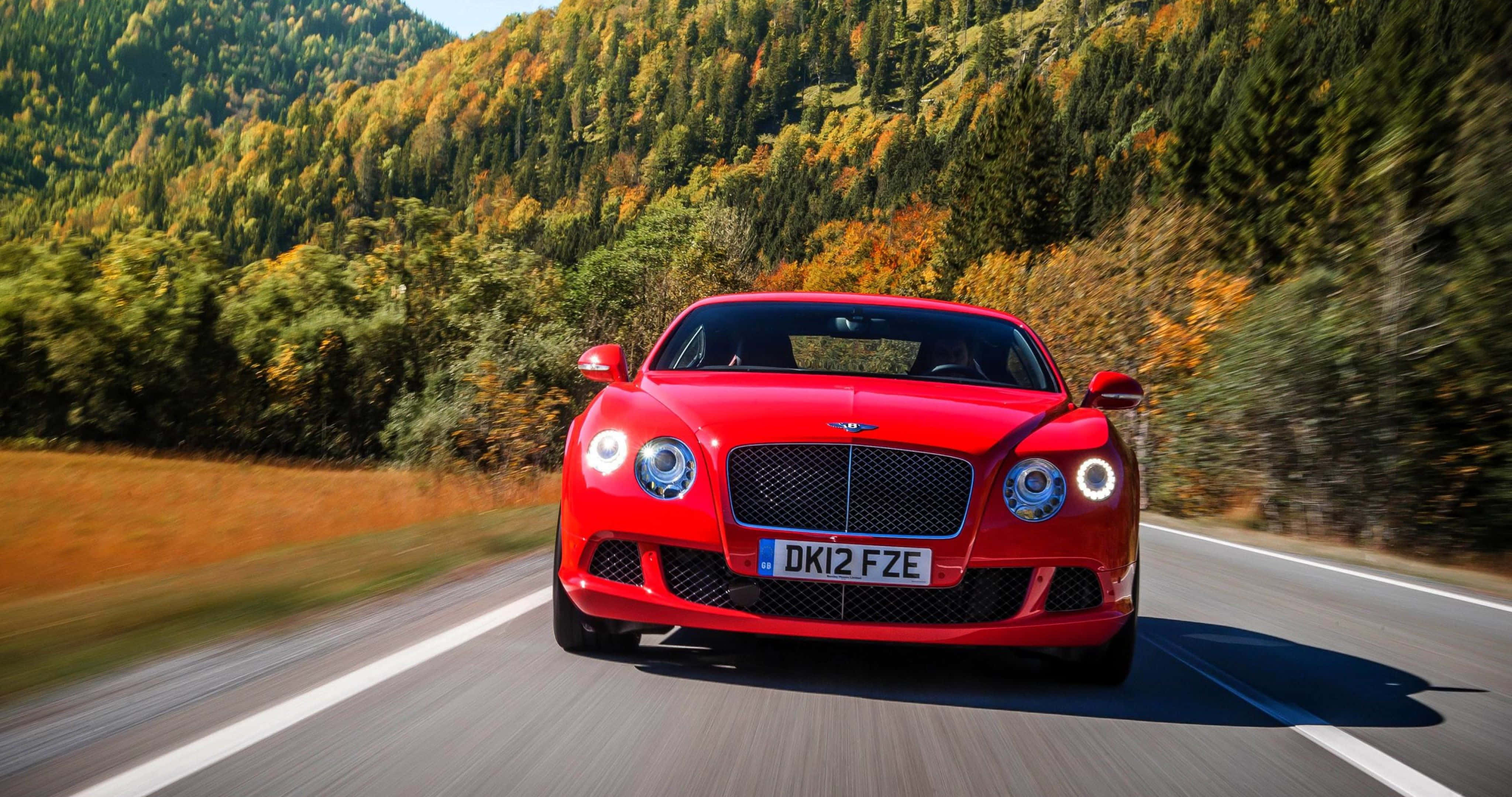 Best Bentley 桌布 壁紙 — 一輛充滿活力的紅色賓利在蜿蜒的山路上疾馳，周圍環繞著秋天的樹葉。