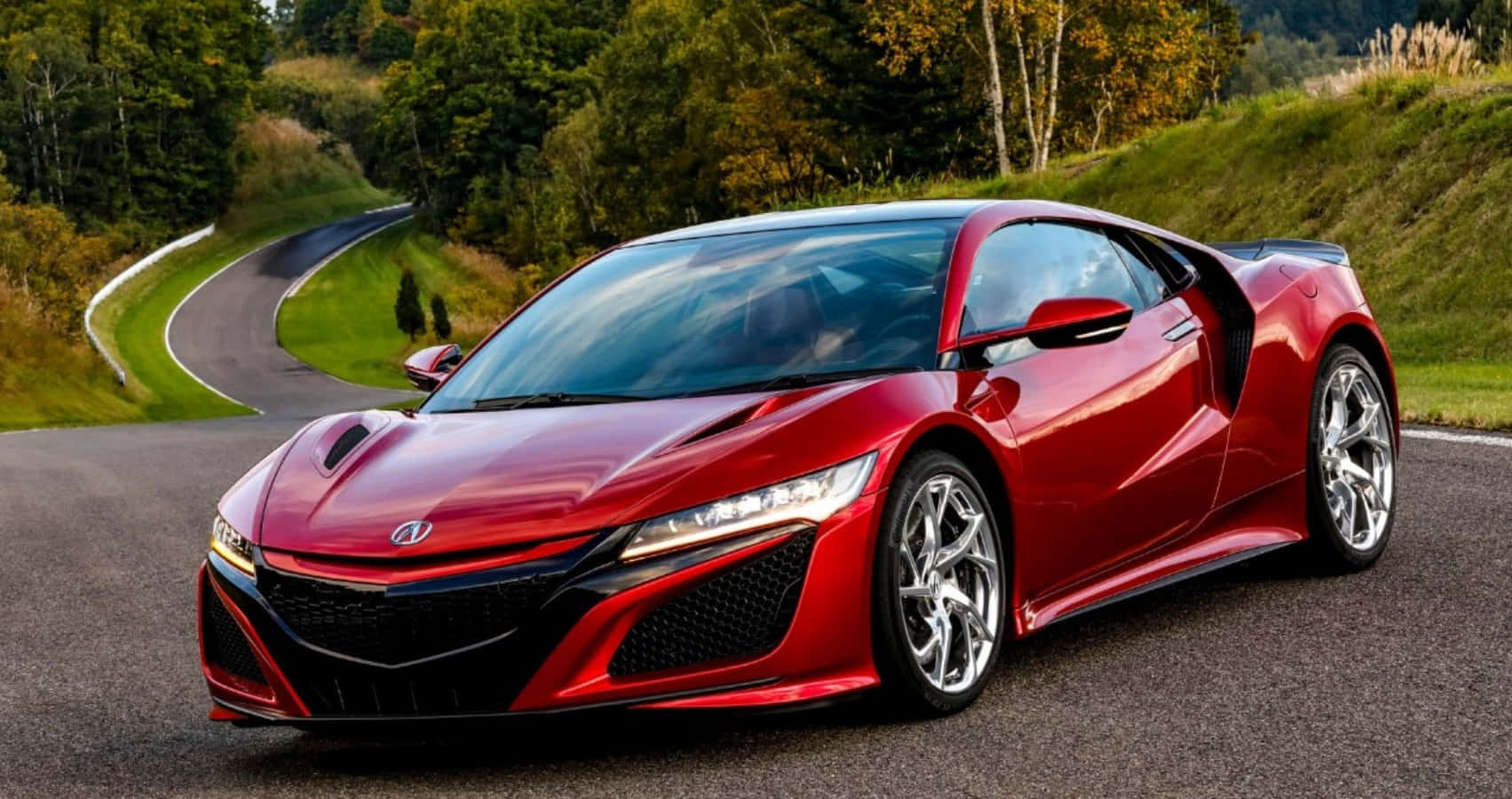 Acura 桌布 壁紙 — 一輛充滿活力的紅色跑車，採用時尚的空氣動力學設計，在明亮的日光下沿著蜿蜒的森林道路行駛。