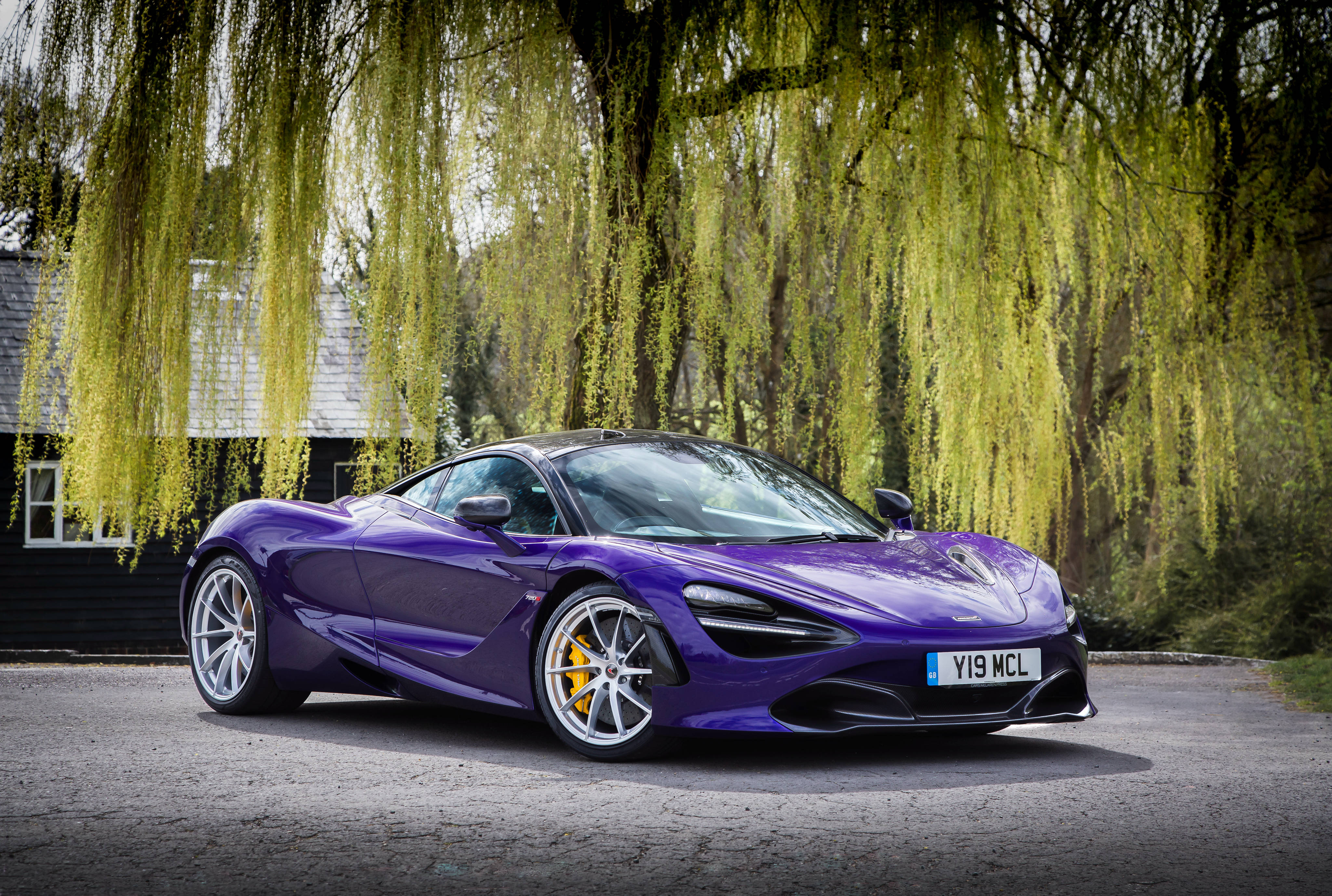 麥拉倫 720S 桌布 壁紙 — 一輛充滿活力的紫色McLaren 720S跑車在日光下閃耀，垂柳樹下金綠色的葉子隨風飄揚。
