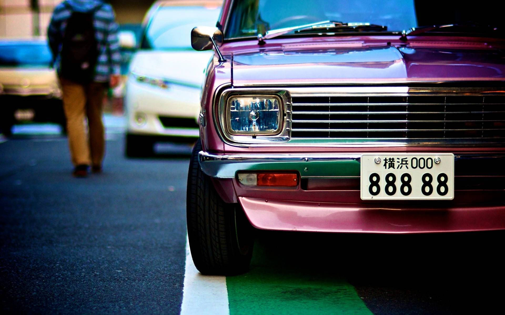 跑車 桌布 壁紙 — 一輛充滿活力的紫色復古車停在街上，一位行人以柔焦效果走過。