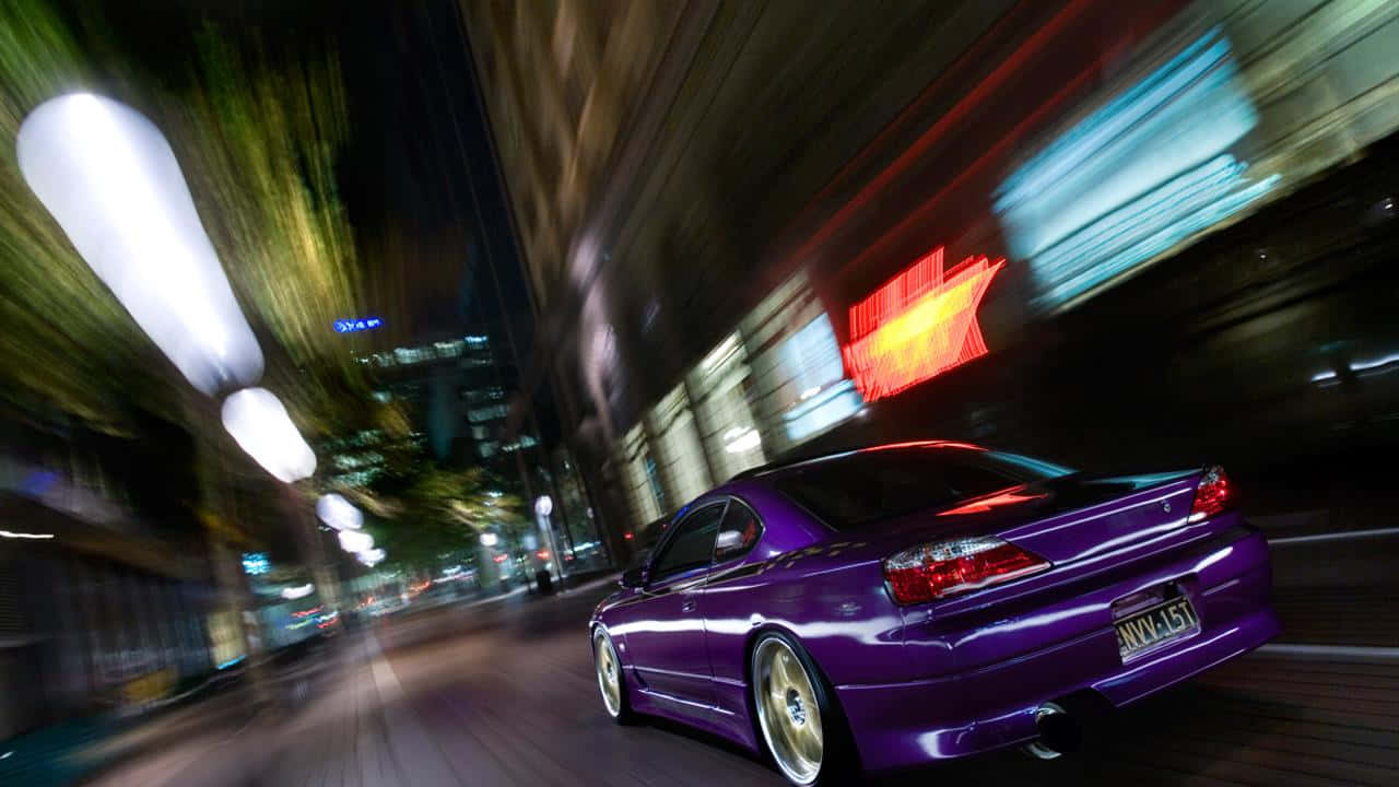 東京 桌布 壁紙 — 一輛充滿活力的紫色跑車在夜晚霓虹燈閃爍的街道上疾馳，伴隨著流動的光線和模糊的建築物。
