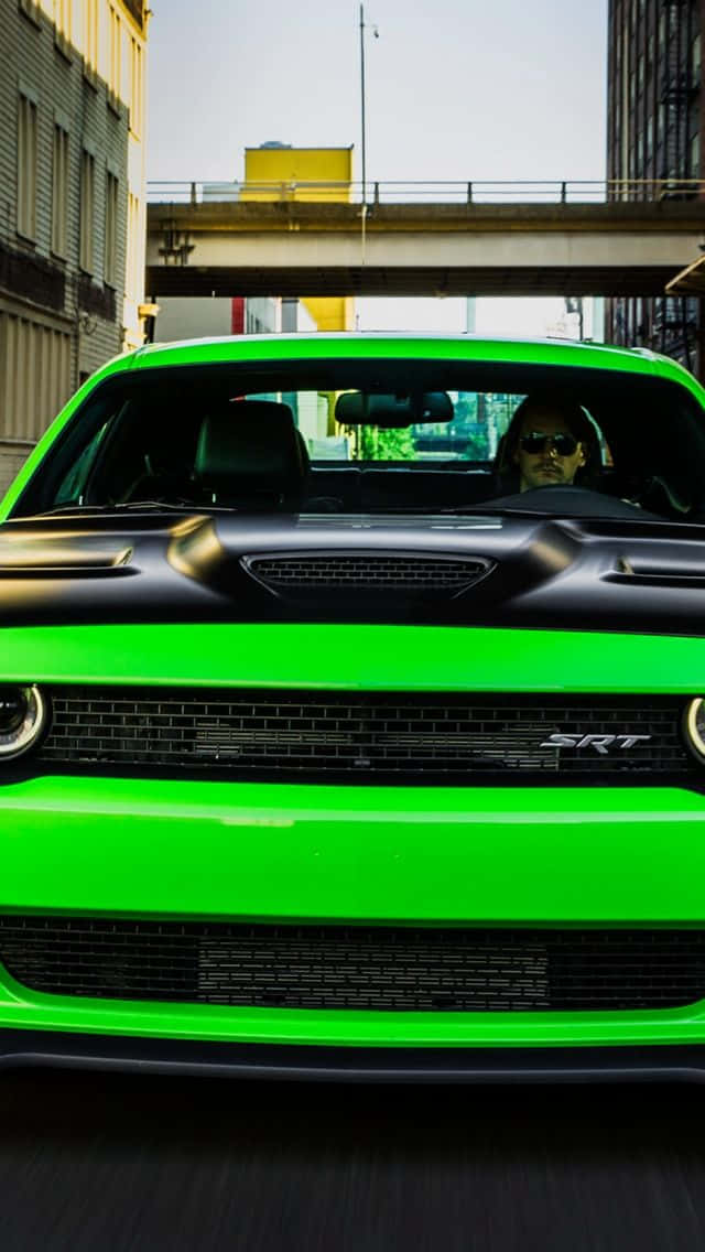 復古 桌布 壁紙 — 一輛充滿活力的綠色 Dodge Challenger SRT 在混凝土天橋下的城市峽谷中疾馳，司機戴著太陽眼鏡。