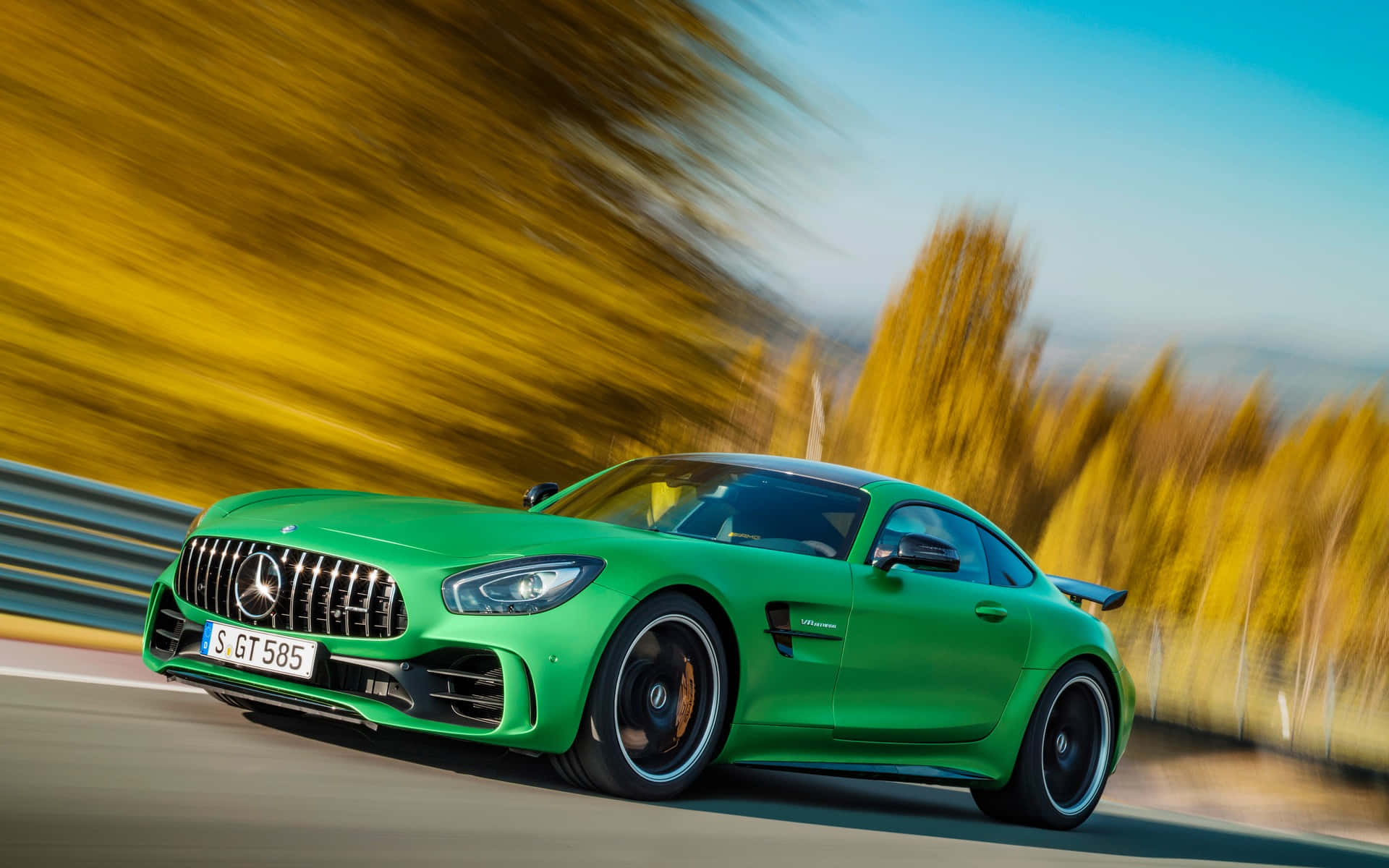 汽車 桌布 壁紙 — 一輛充滿活力的綠色 Mercedes-AMG GT R 在道路上奔馳，金色的秋樹在運動中模糊掠過。