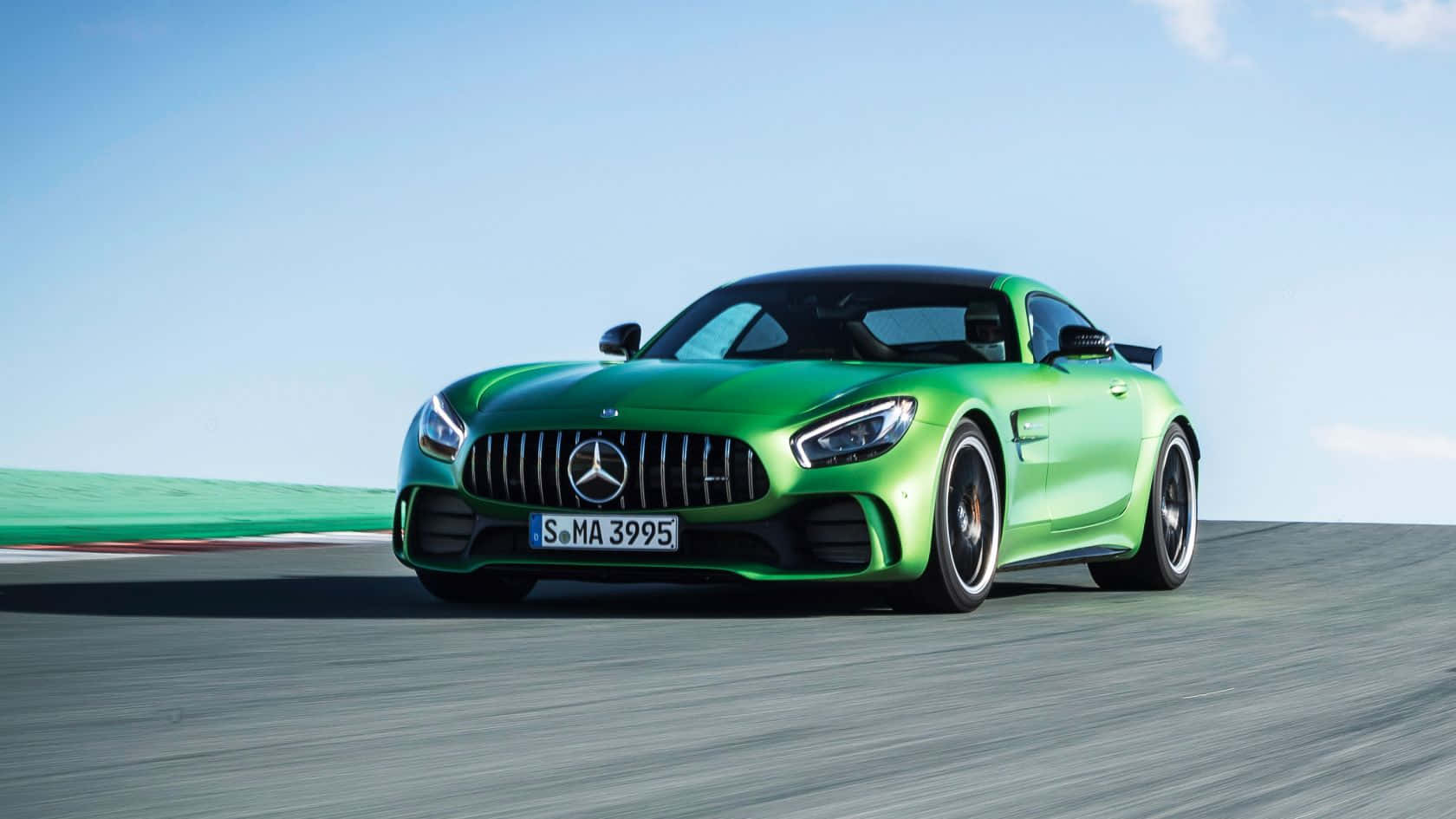 汽車 桌布 壁紙 — 一輛充滿活力的綠色 Mercedes-AMG GT R 跑車在晴朗的藍天下沿著賽道飛馳。