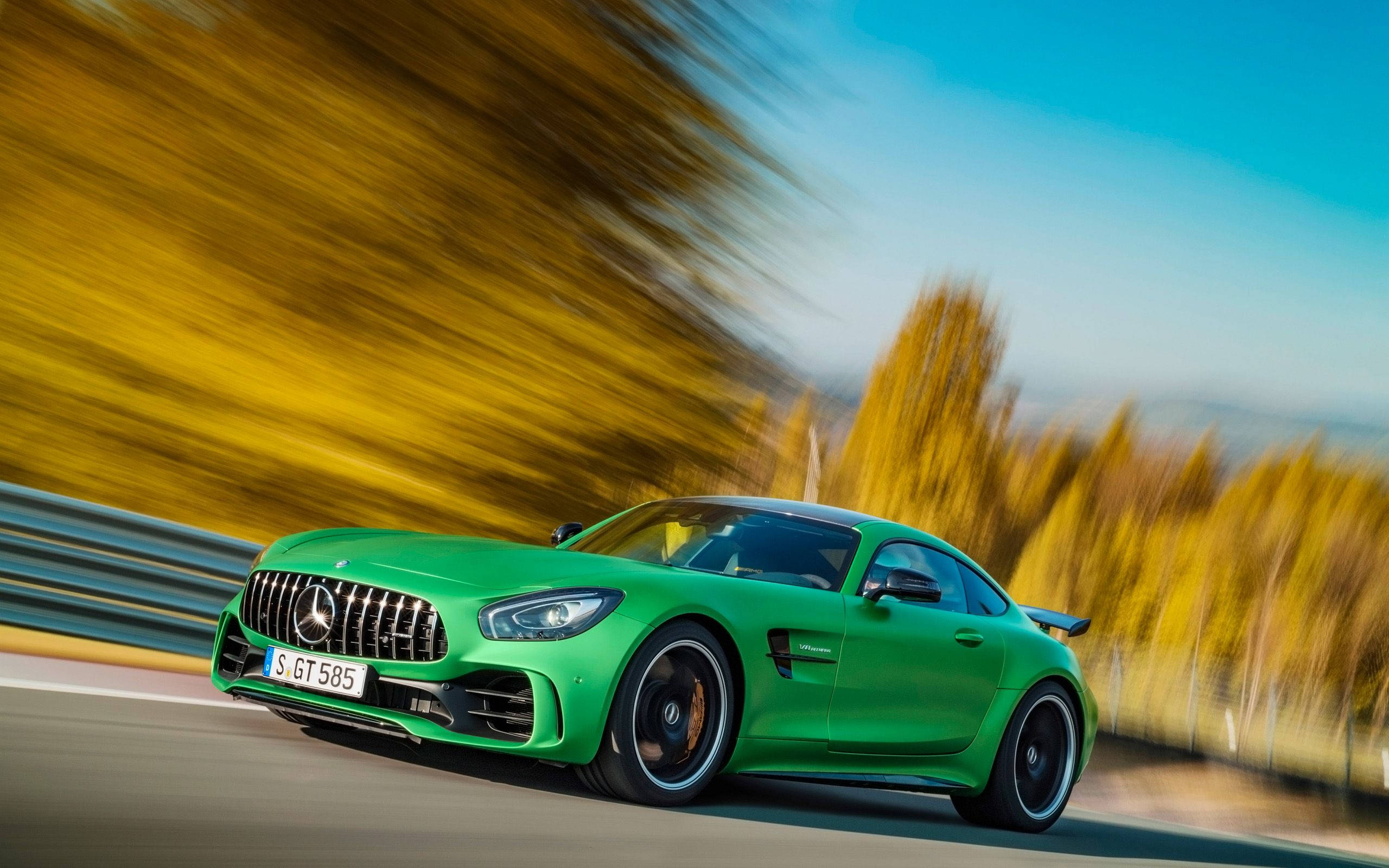 Gtr 桌布 壁紙 — 一輛充滿活力的綠色 Mercedes-AMG GT R 沿著蜿蜒的道路疾馳，金色的秋樹在運動中模糊掠過。