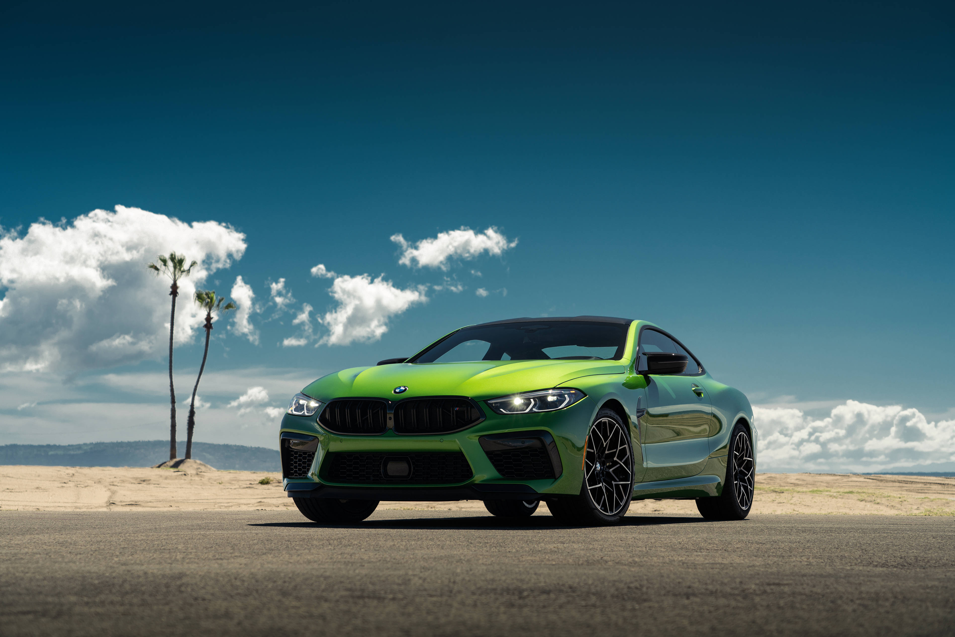 4K BMW 壁紙 桌布 壁紙 — 一輛充滿活力的綠色BMW M2雙門跑車停在瀝青路上，背景是明亮的藍天、散落的雲朵和棕櫚樹。