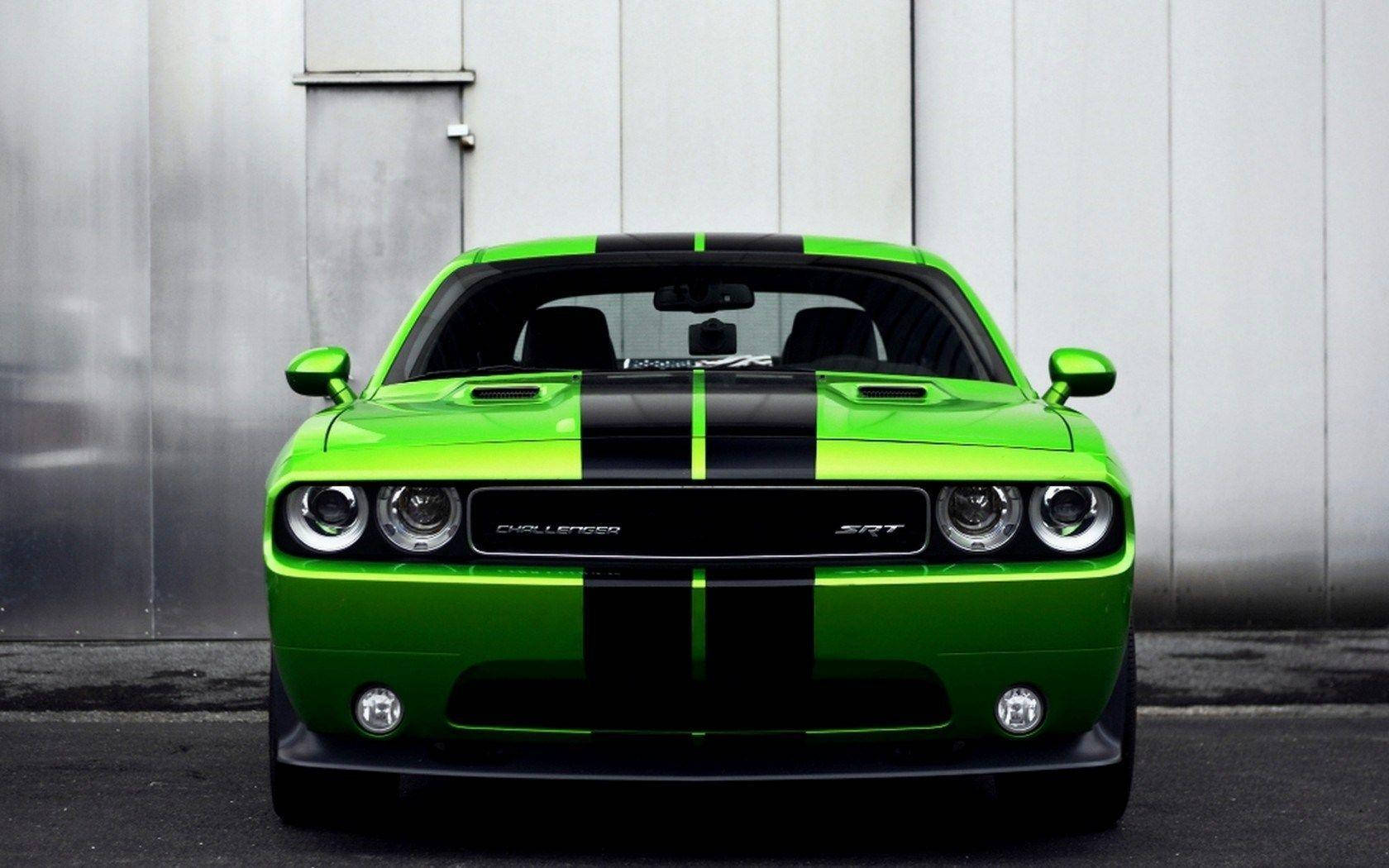 Challenger 桌布 壁紙 — 一輛充滿活力的綠色Dodge Challenger SRT帶有黑色賽車條紋，正面朝向金屬灰色工業牆。
