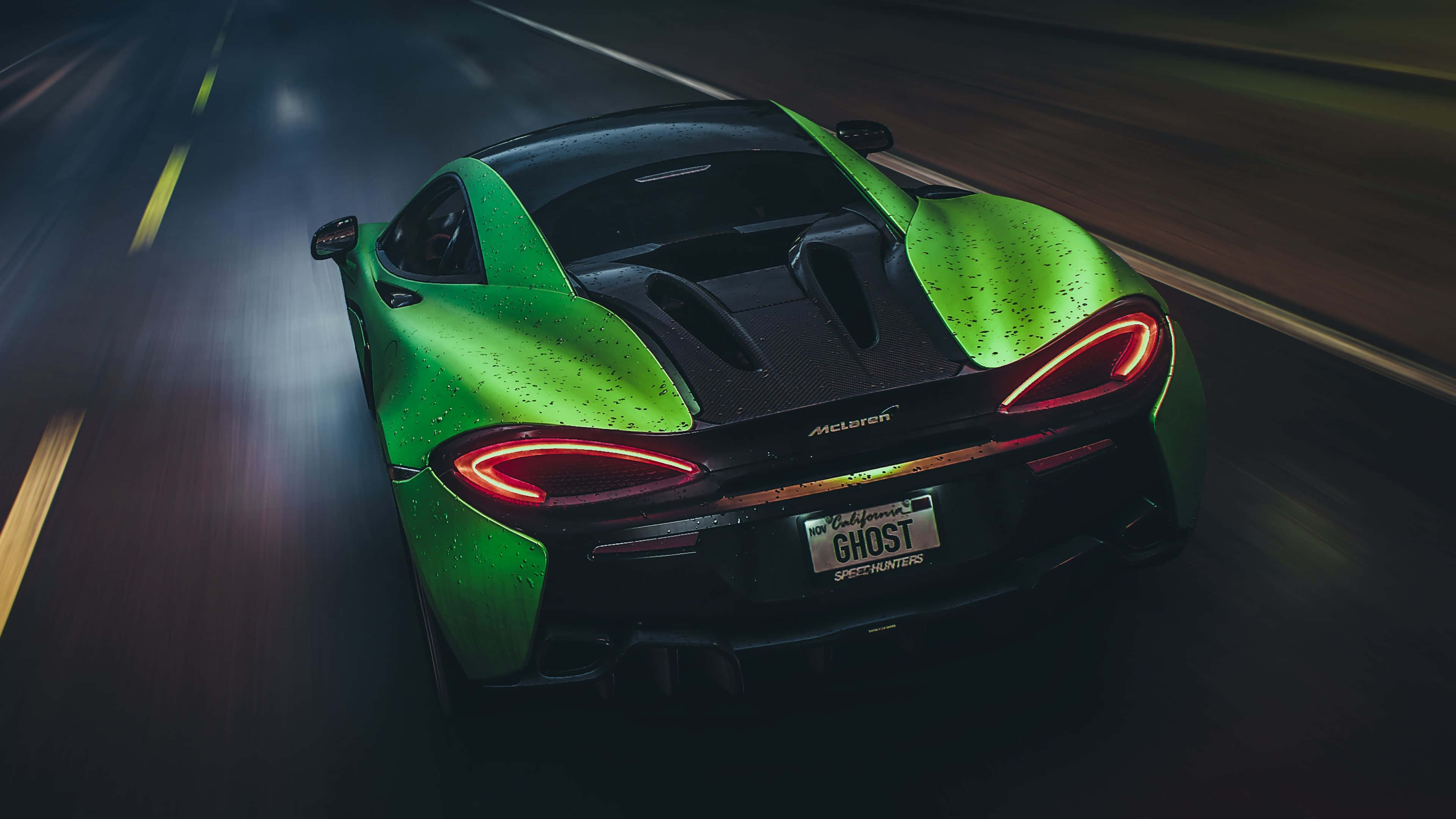Need For Speed 4K 桌布 壁紙 — 一輛充滿活力的綠色McLaren跑車在潮濕的夜路上疾馳，紅色尾燈閃爍，帶有動態模糊效果。
