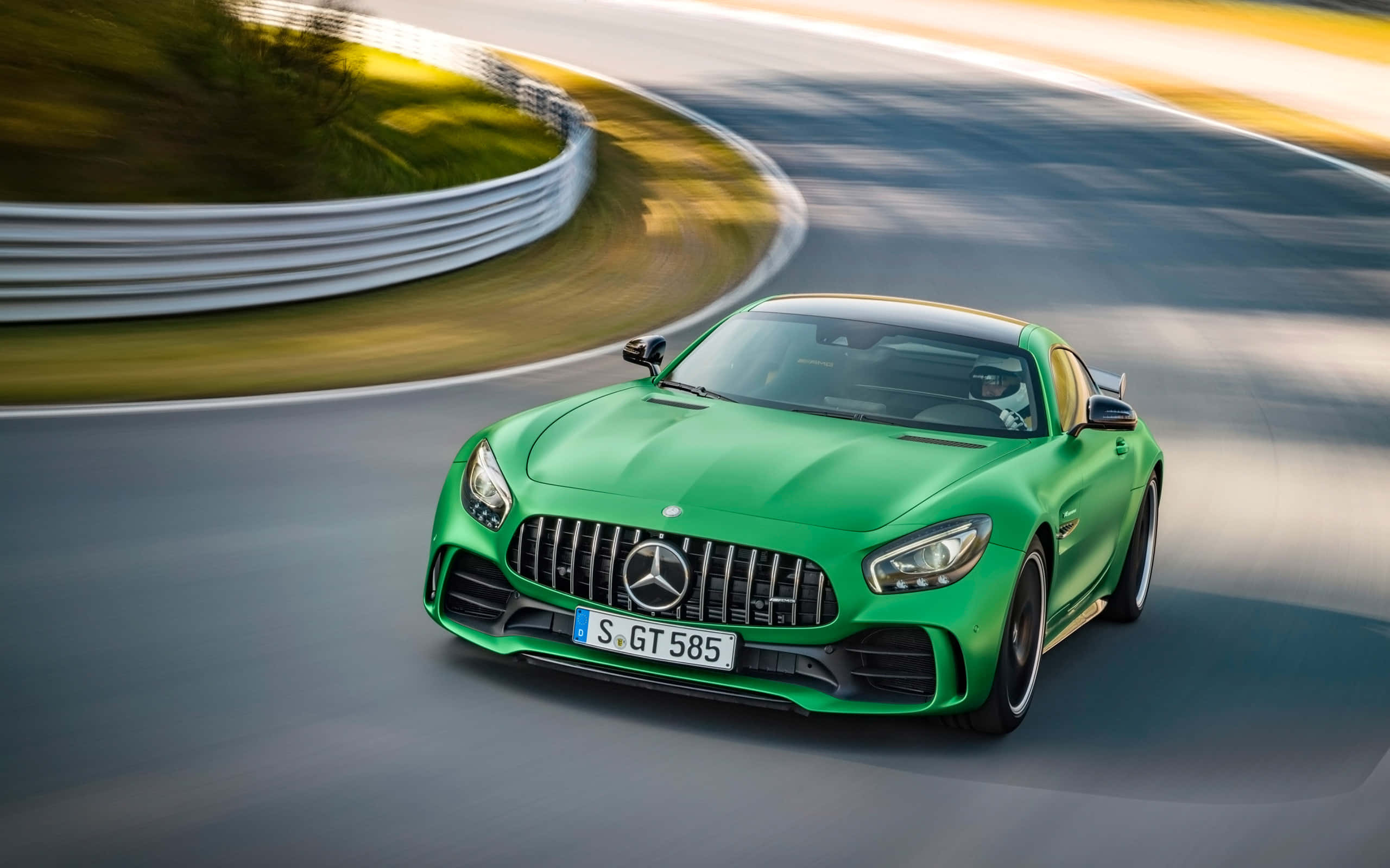 Mercedes 桌布 壁紙 — 一輛充滿活力的綠色Mercedes-AMG GT S在彎曲的賽道上奔馳，帶有模糊的動態和金色的陽光。