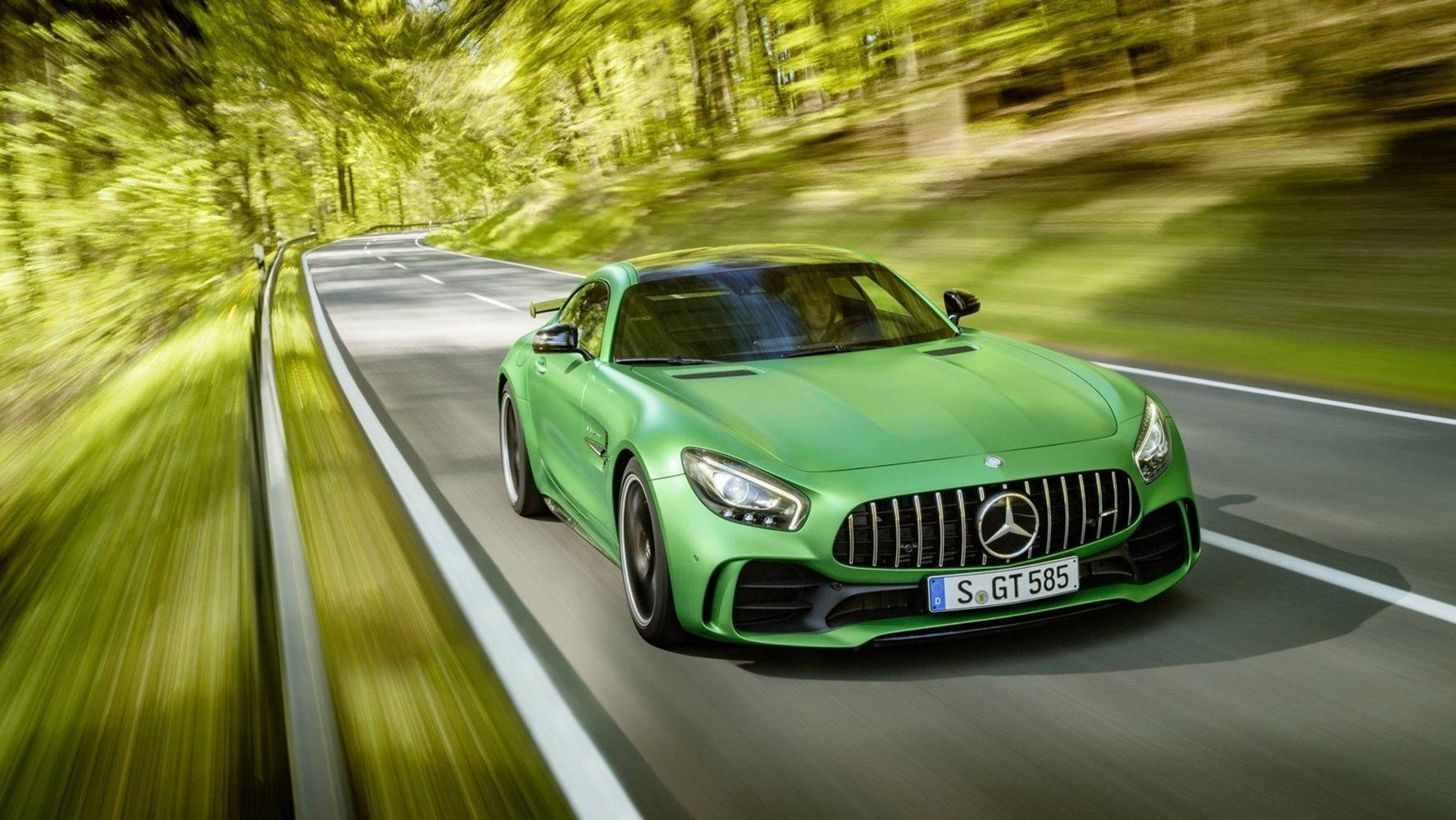 Gtr 桌布 壁紙 — 一輛充滿活力的綠色Mercedes-AMG GT S在蜿蜒的森林道路上疾馳，周圍環繞著動態模糊效果。