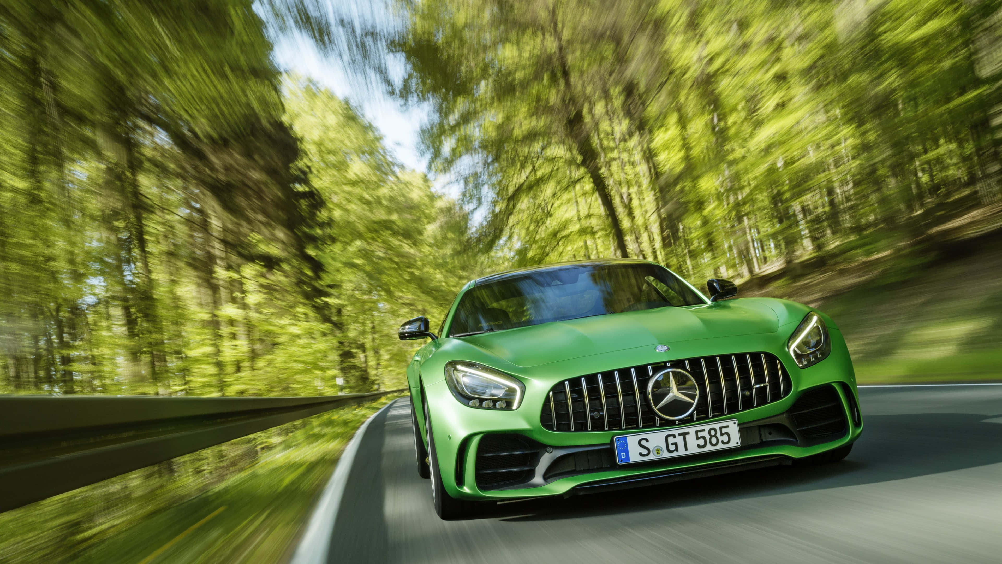 Mercedes 桌布 壁紙 — 一輛充滿活力的綠色Mercedes-AMG GT S在陽光明媚的森林中疾馳，動態模糊強調了速度。