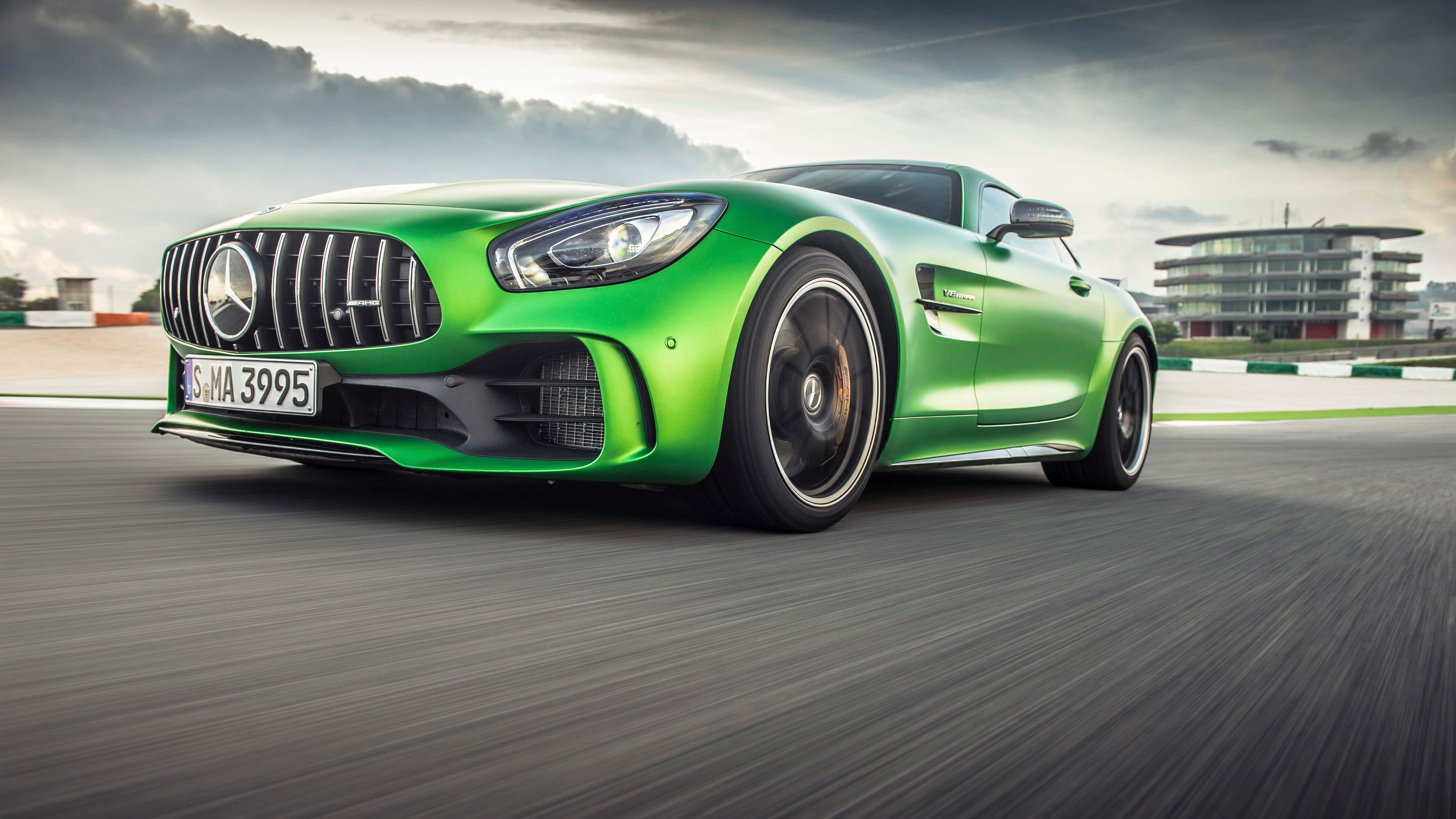 Mercedes 桌布 壁紙 — 一輛充滿活力的綠色Mercedes-AMG GT S在陰天下的賽道上疾馳，瀝青路面呈現動態模糊效果。