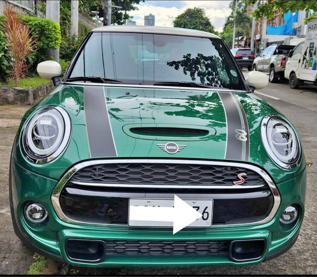 Mini 桌布 壁紙 — 一輛充滿活力的綠色MINI Cooper S，帶有黑色賽車條紋，停在綠樹成蔭的城市街道上。