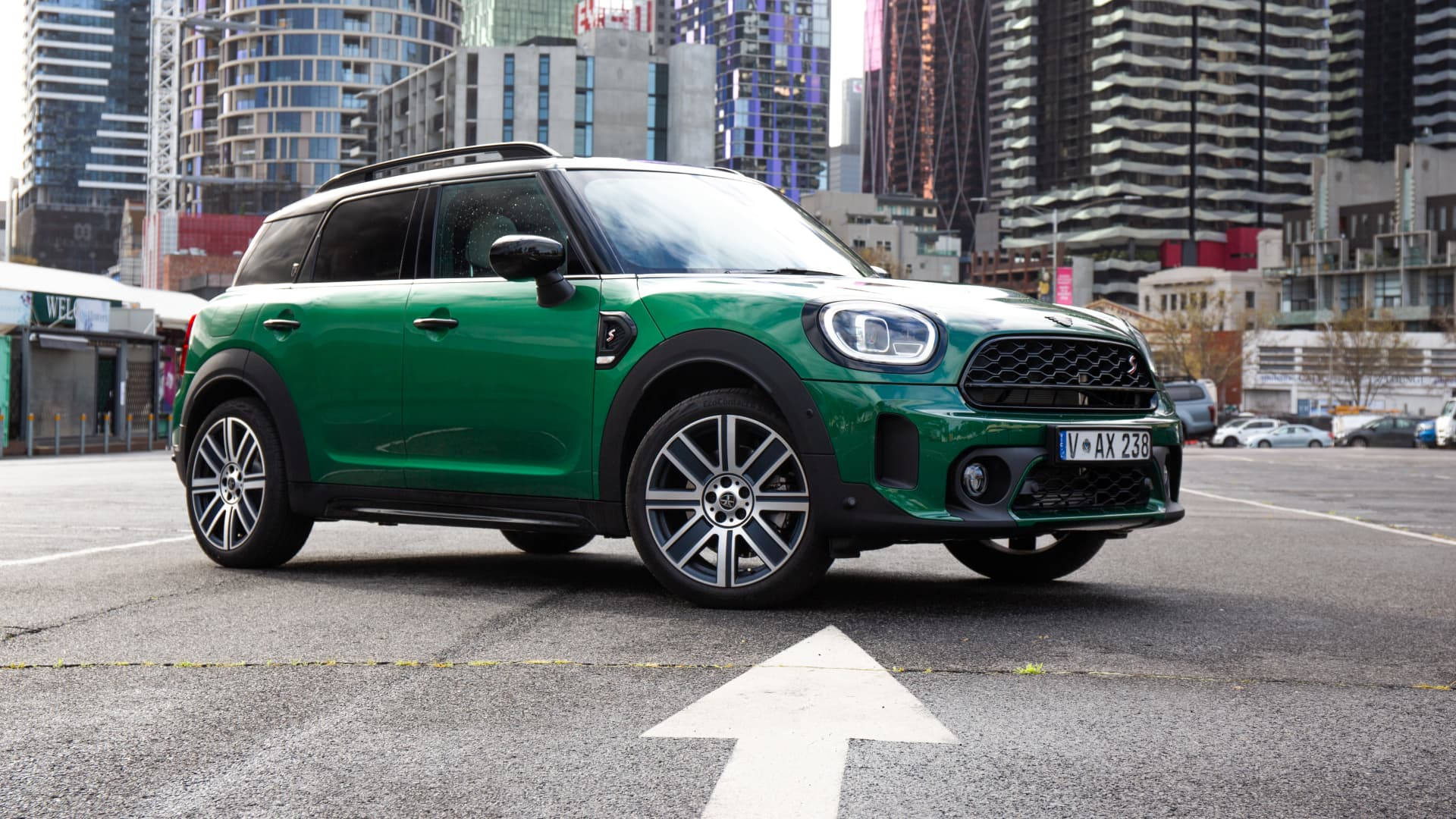 城市 桌布 壁紙 — 一輛充滿活力的綠色MINI Countryman SUV停放在城市地塊上，背景是現代摩天大樓。