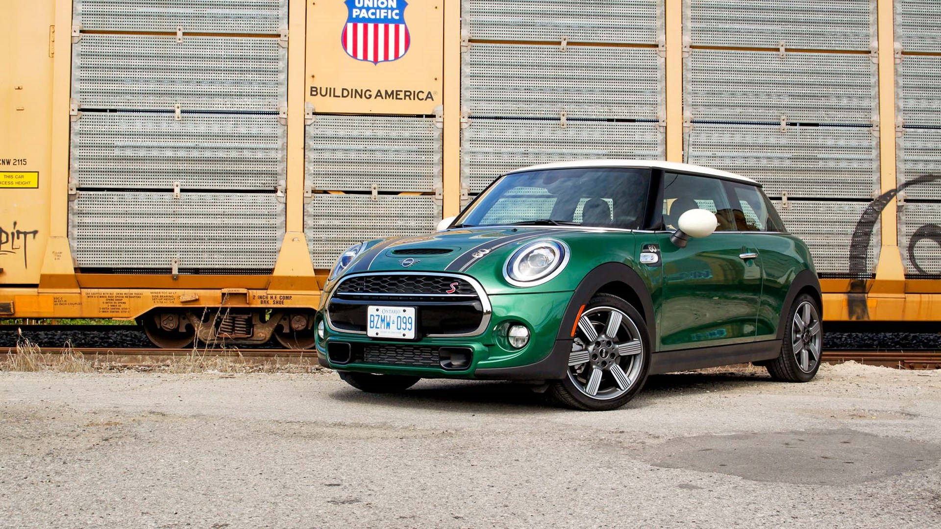 Mini 桌布 壁紙 — 一輛充滿活力的綠色MINI Cooper S停泊在碎石上，旁邊是一輛黃色的聯合太平洋貨運火車車廂。