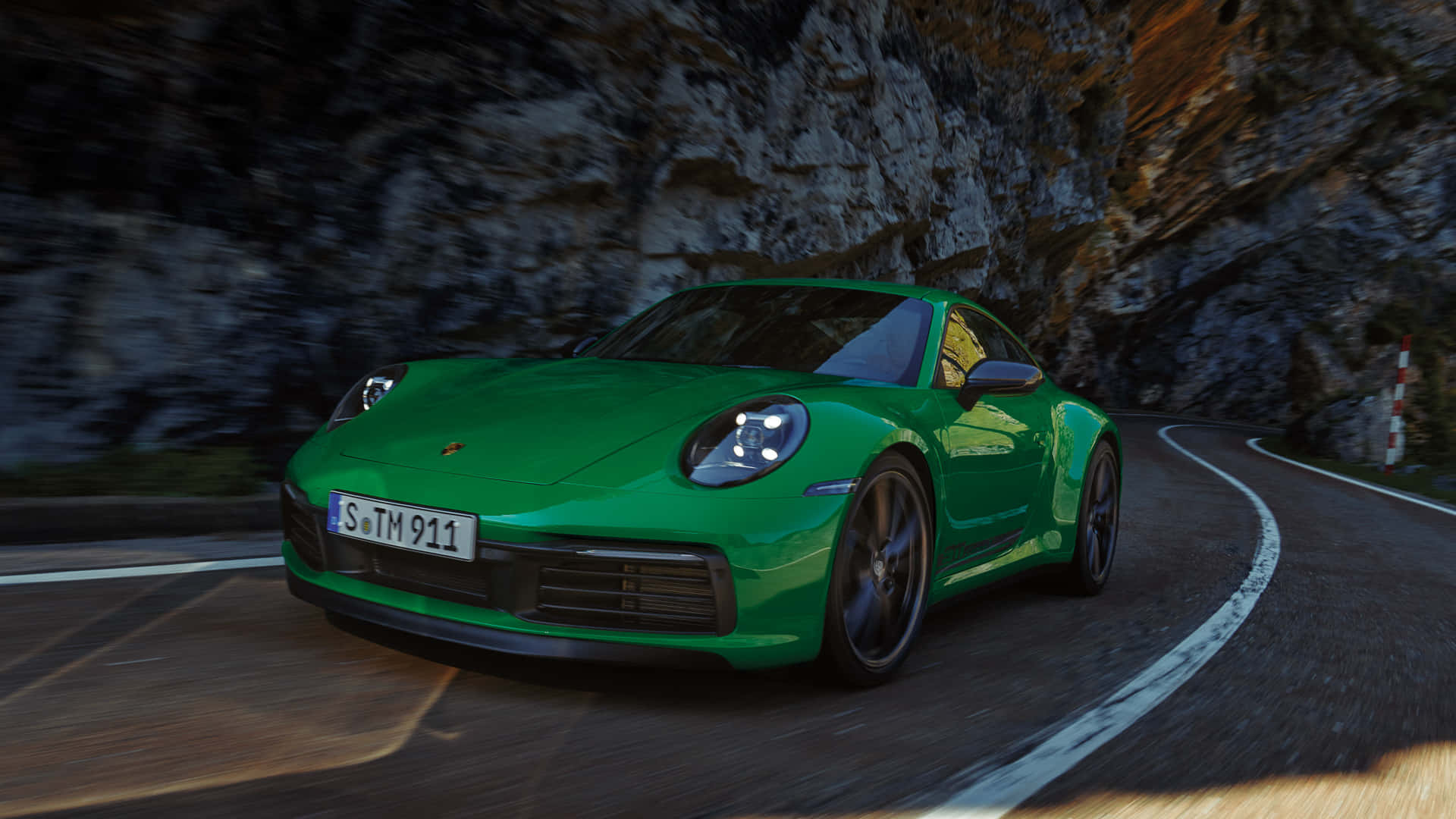 1920 X 1080 Car 桌布 壁紙 — 一輛充滿活力的綠色保時捷911沿著蜿蜒的山路疾馳，背景是模糊的岩石懸崖。
