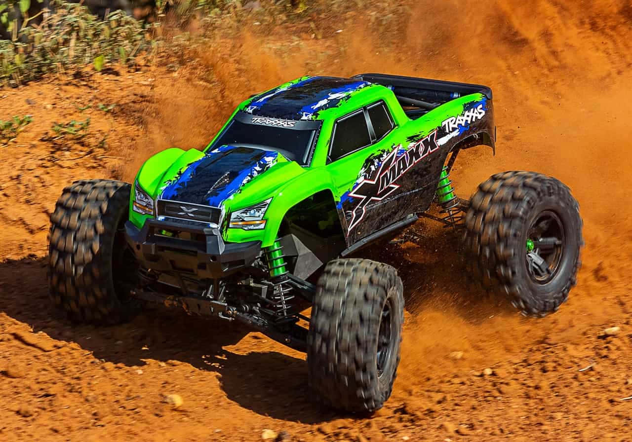 Rc Cars 桌布 壁紙 — 一輛充滿活力的綠色和藍色遙控怪獸卡車在崎嶇的泥土地形上疾馳，揚起紅色塵土。
