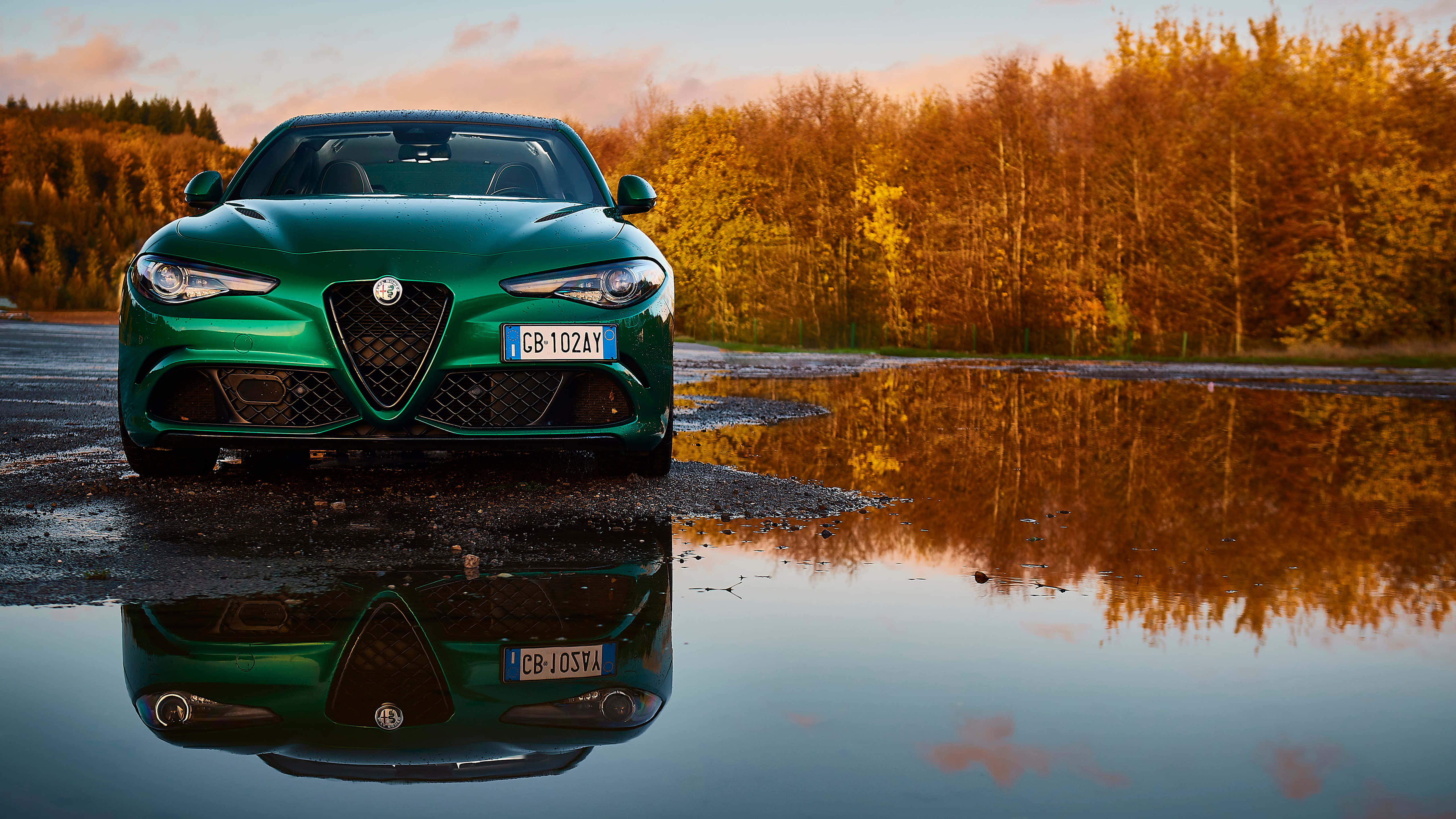 Alfa Romeo 159 桌布 壁紙 — 一輛充滿活力的綠色愛快羅密歐跑車完美地倒映在夕陽下被秋樹環繞的水坑中。