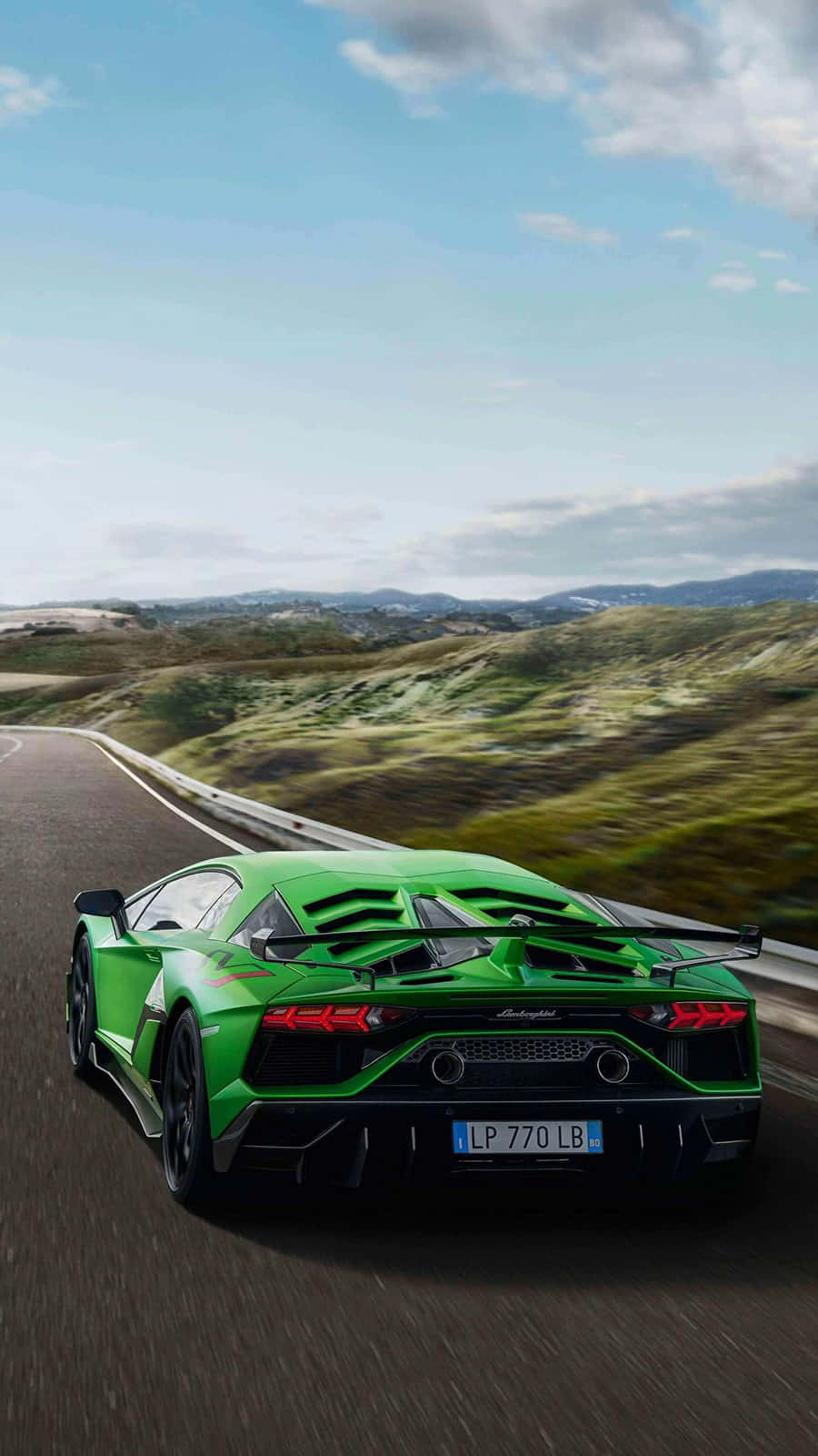 Pixel 3xl Lamborghini 桌布 壁紙 — 一輛充滿活力的綠色藍寶堅尼 Aventador 在部分多雲的天空下，沿著蜿蜒的山路飛馳。
