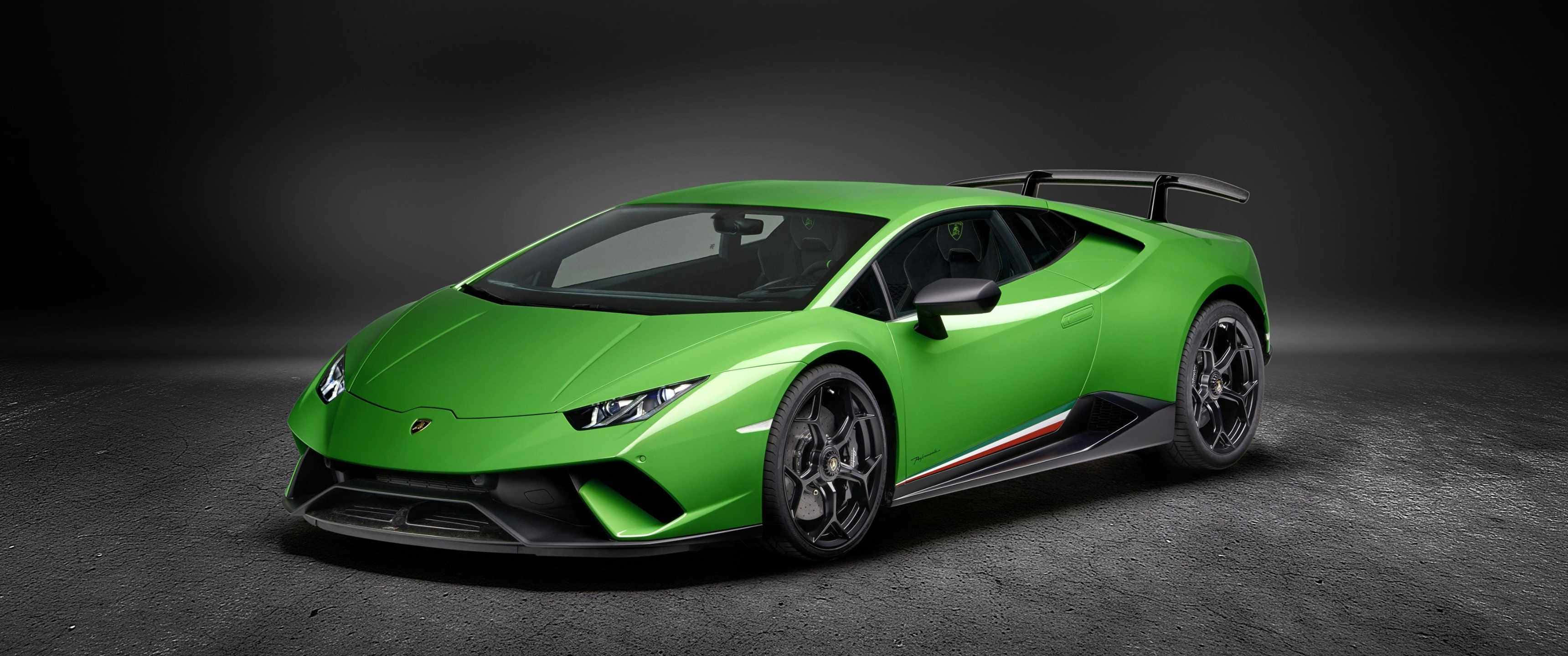 3440x1440p Lamborghini 桌布 壁紙 — 一輛充滿活力的綠色藍寶堅尼Huracán Performante跑車，帶有黑色飾件和後擾流板，在昏暗的攝影棚中配合戲劇性燈光展示。