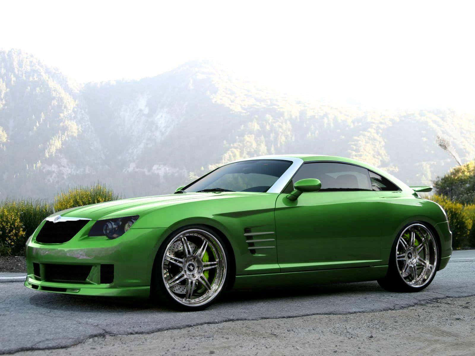 Chrysler Crossfire 桌布 壁紙 — 一輛充滿活力的綠色跑車，配備定制鍍鉻輪圈，停泊在背景有森林覆蓋山丘的山路上。