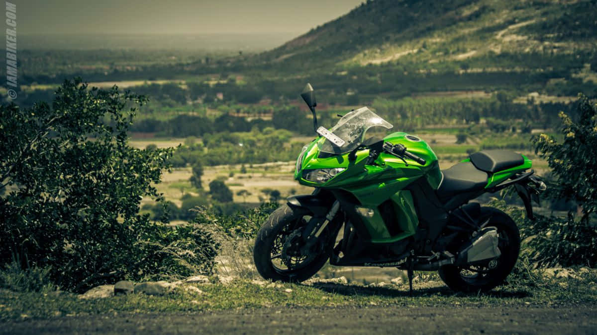 Kawasaki Desktop 桌布 壁紙 — 一輛充滿活力的綠色運動機車停放在一個草坡上，俯瞰著一個廣闊的山谷，遠處有山丘。