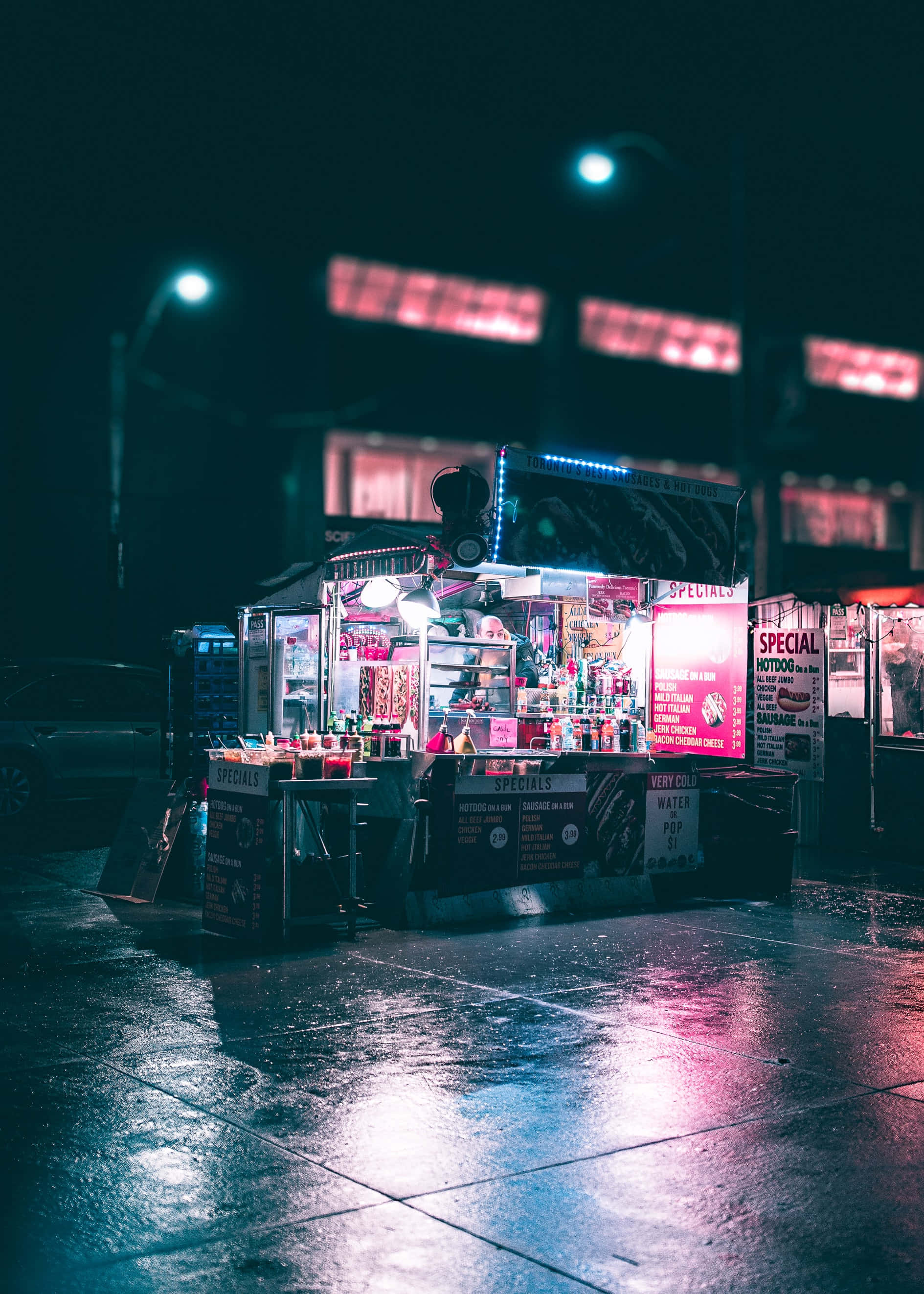 高清 桌布 壁紙 — 一輛充滿活力的美食車在夜晚潮濕的城市街道上，在霓虹燈下閃耀，將繽紛色彩反射在路面上。