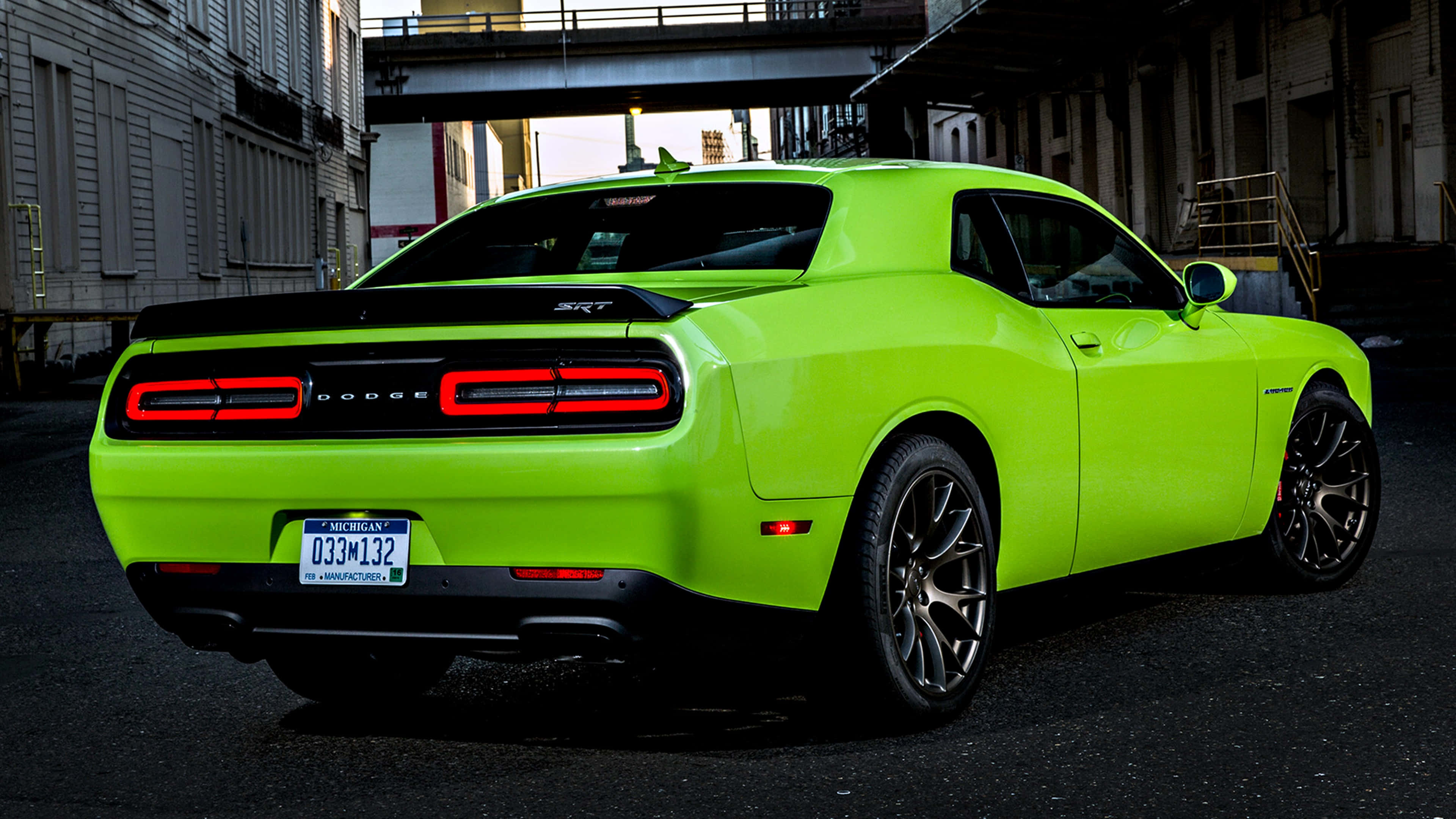 桌布 壁紙 — 一輛充滿活力的萊姆綠色 Dodge Challenger SRT 停放在城市高架橋下，紅色尾燈閃爍發光。
