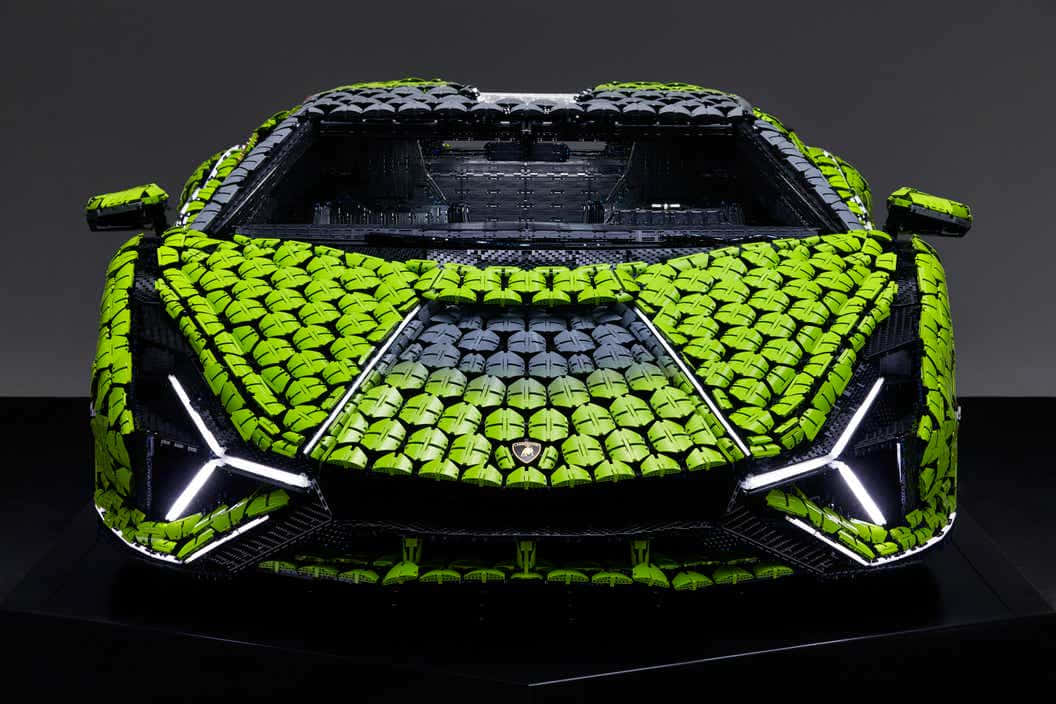 Cool Lamborghinis 桌布 壁紙 — 一輛充滿活力的萊姆綠色LEGO藍寶堅尼Aventador，帶有發光的白色頭燈和黑色飾邊，在深色工作室背景前展示。