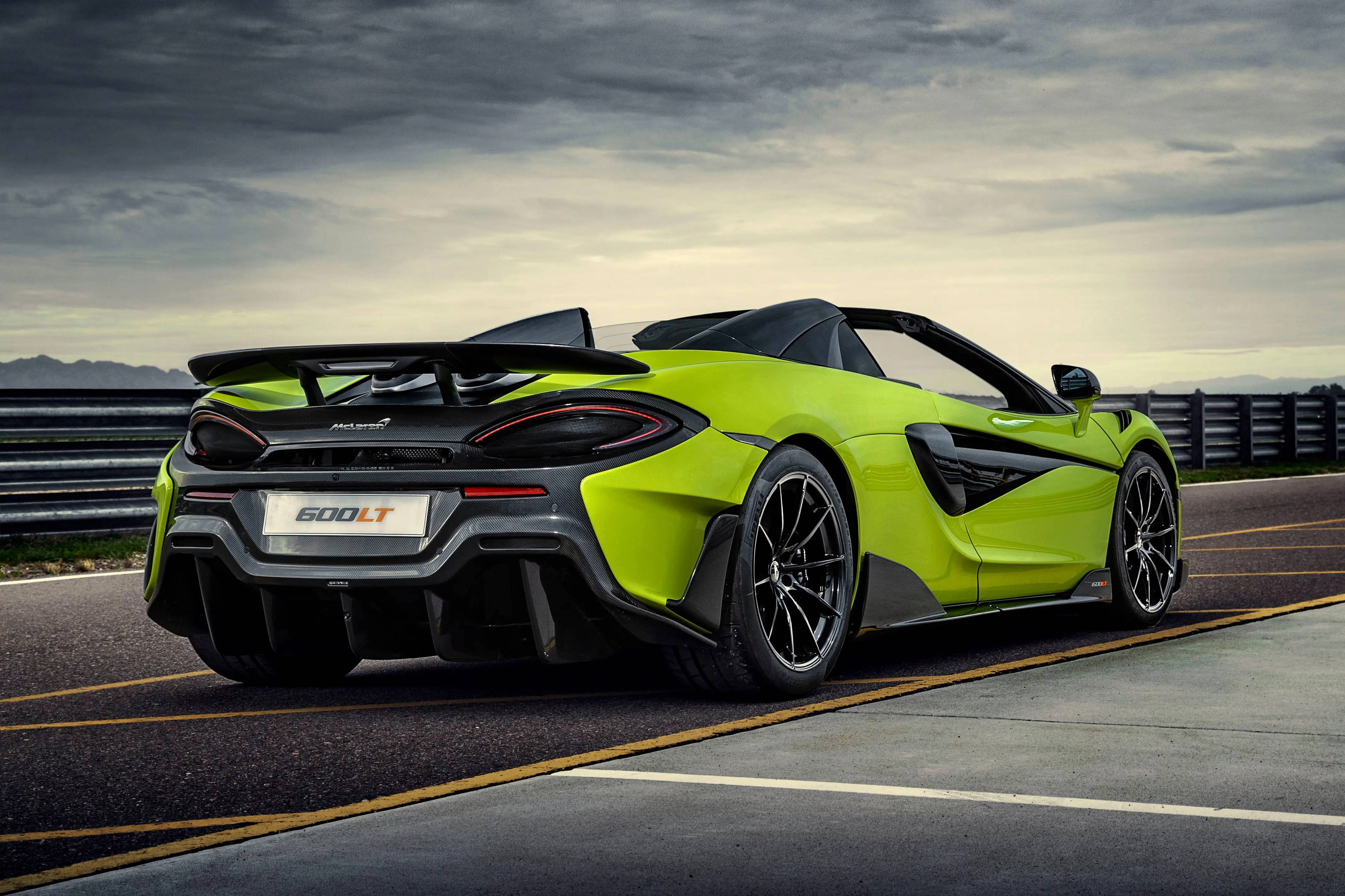 跑車 桌布 壁紙 — 一輛充滿活力的萊姆綠色McLaren 600LT Spider敞篷跑車停放在賽道上，天空多雲。