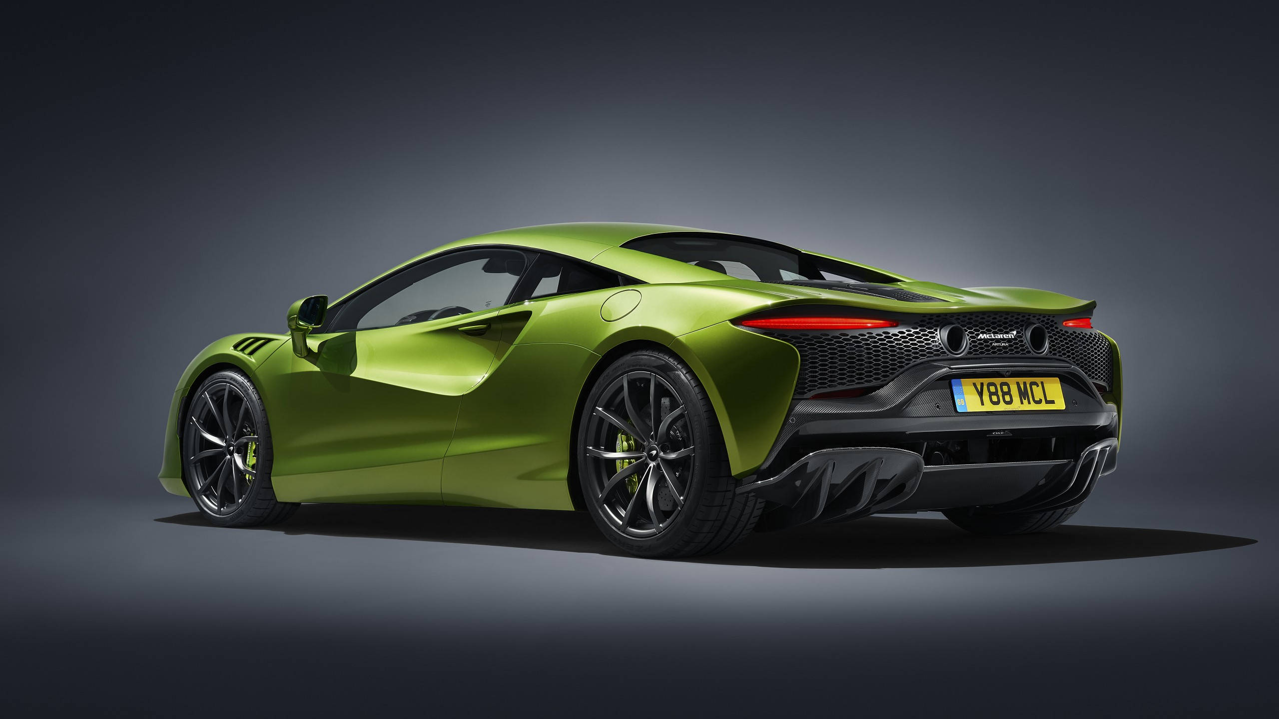 跑車 桌布 壁紙 — 一輛充滿活力的萊姆綠色McLaren跑車在攝影棚內以戲劇性燈光和深灰色背景展示。