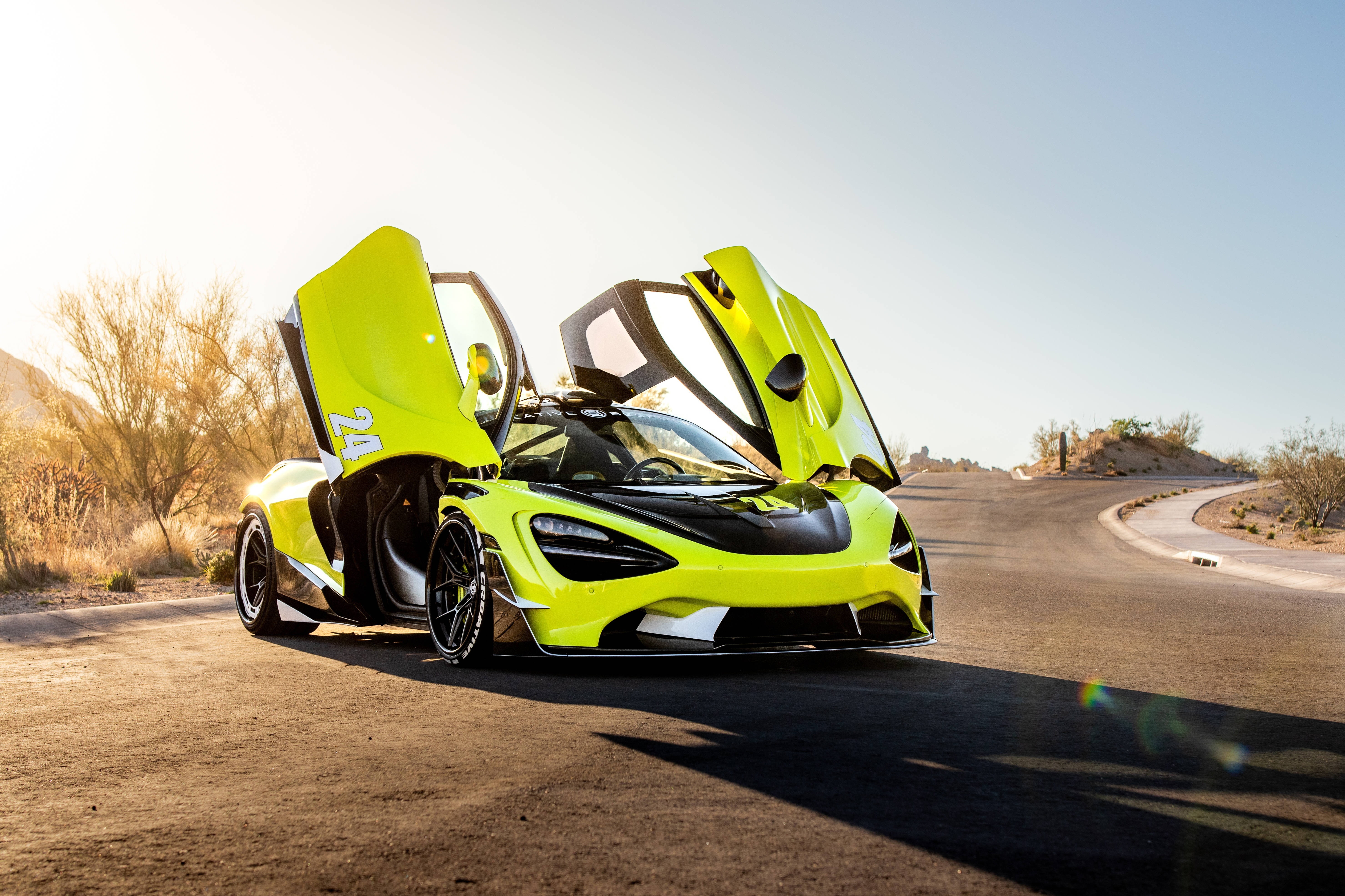 Mclaren 720s 桌布 壁紙 — 一輛充滿活力的萊姆綠色McLaren跑車，鷗翼車門打開，停在陽光明媚的沙漠公路上。