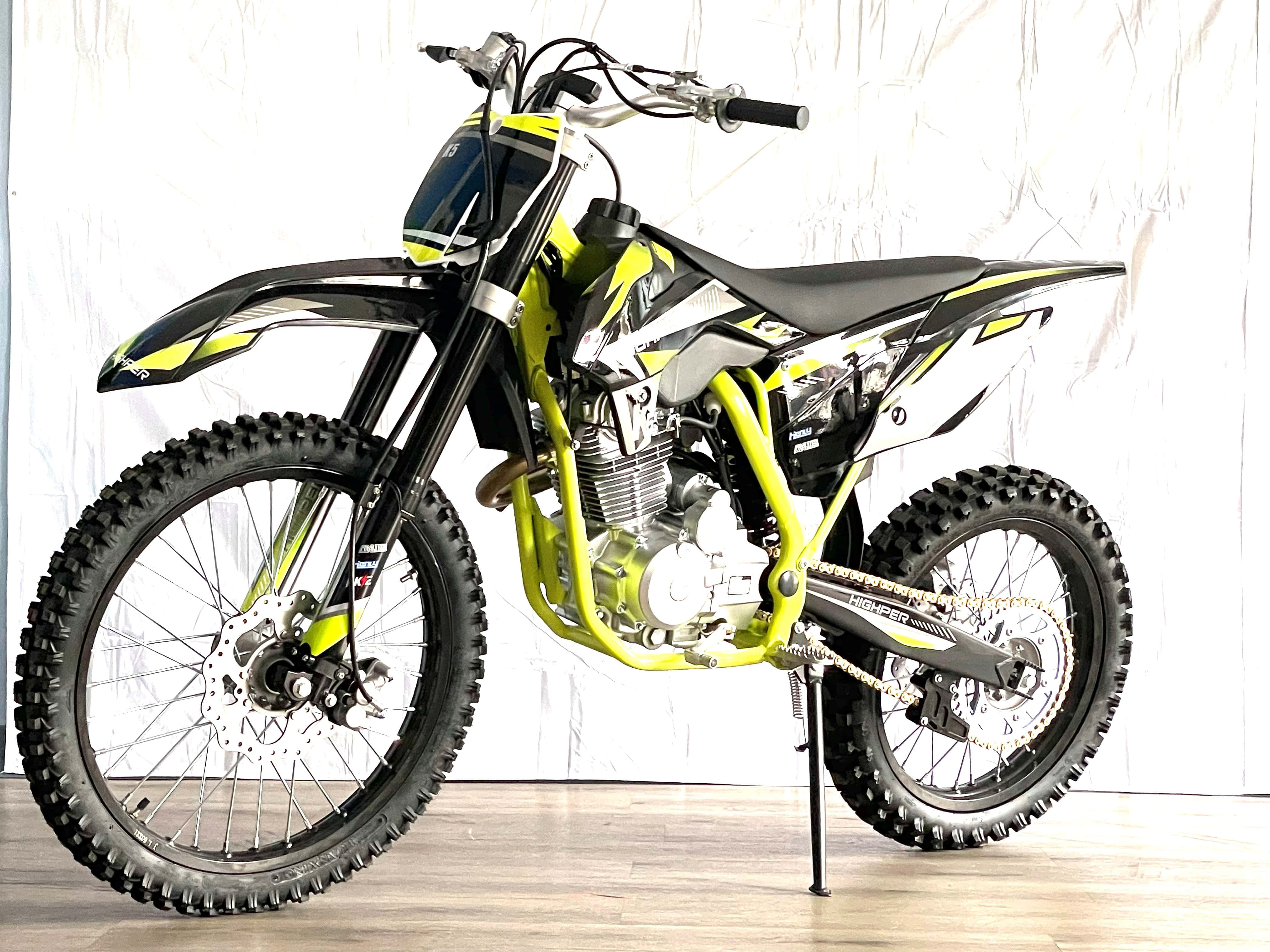 Dirtbike 桌布 壁紙 — 一輛充滿活力的萊姆綠色和黑色越野機車，配備防滑輪胎，以側腳架支撐在白色背景前。