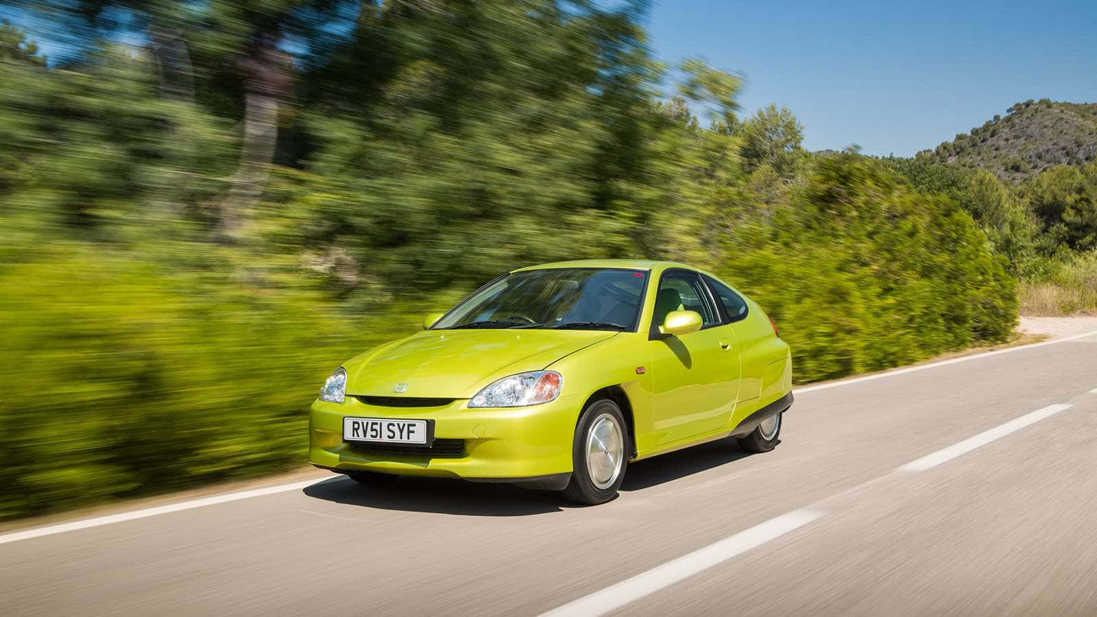 Honda Insight 桌布 壁紙 — 一輛充滿活力的萊姆綠色本田 Insight 在陽光明媚的鄉村道路上疾馳，兩旁茂密的綠樹模糊掠過。