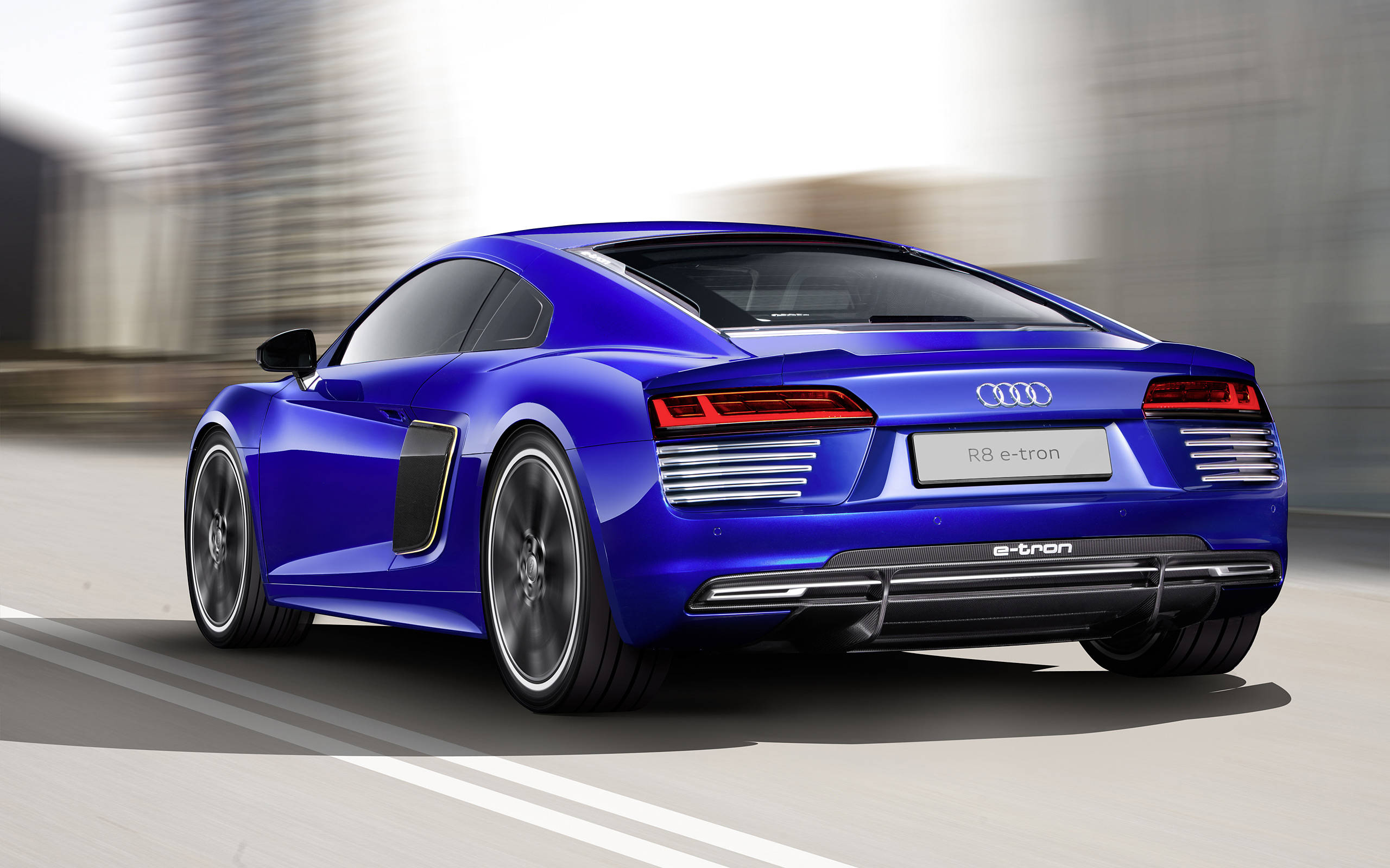 R8 桌布 壁紙 — 一輛充滿活力的藍色 Audi R8 e-tron 跑車在模糊的城市道路上奔馳，展現出流線型設計和電動動力。