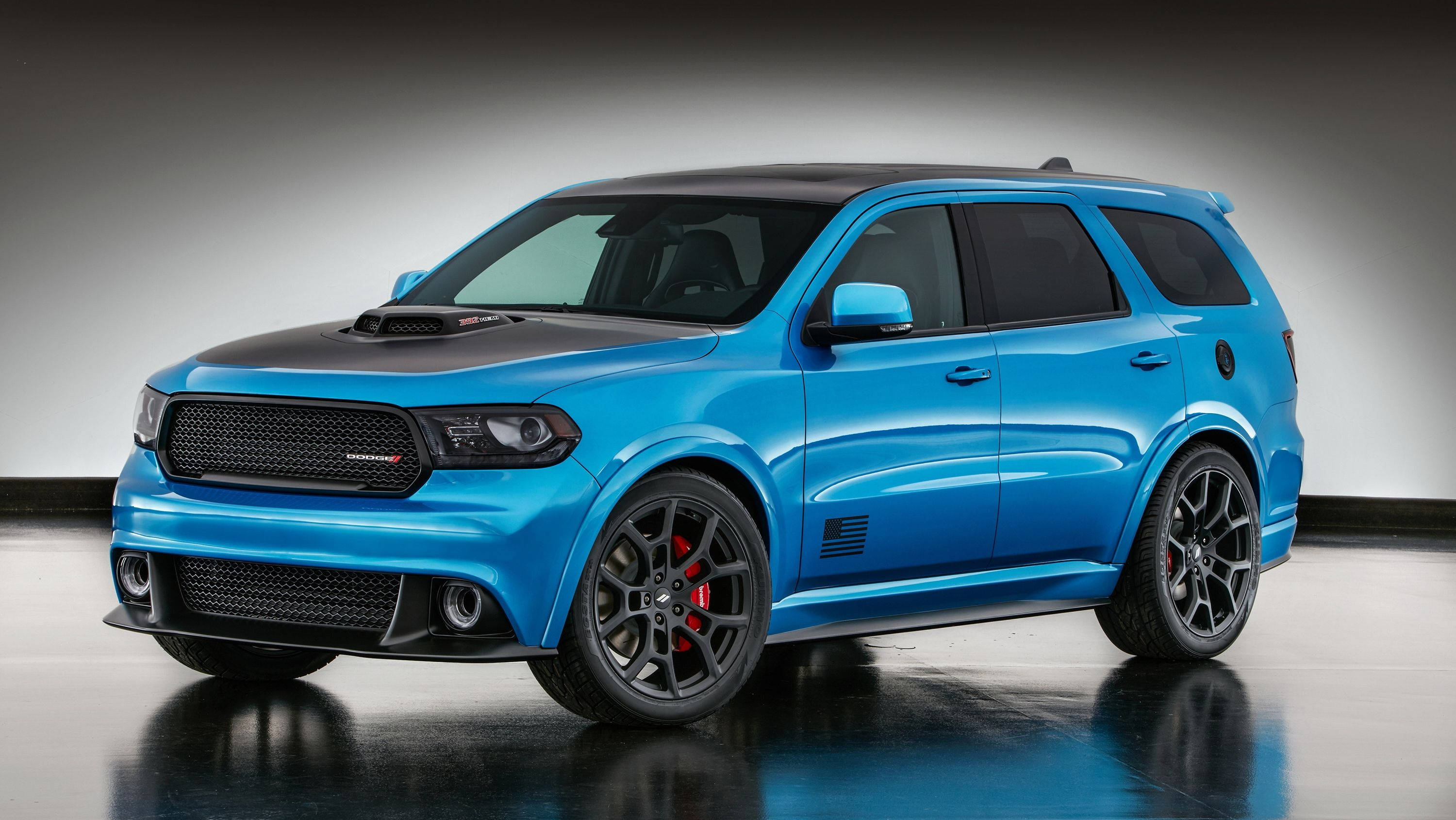 Dodge 桌布 壁紙 — 一輛充滿活力的藍色 Dodge Durango SRT，帶有黑色飾件和紅色制動卡鉗，在反光地板上的工作室燈光下閃閃發光。