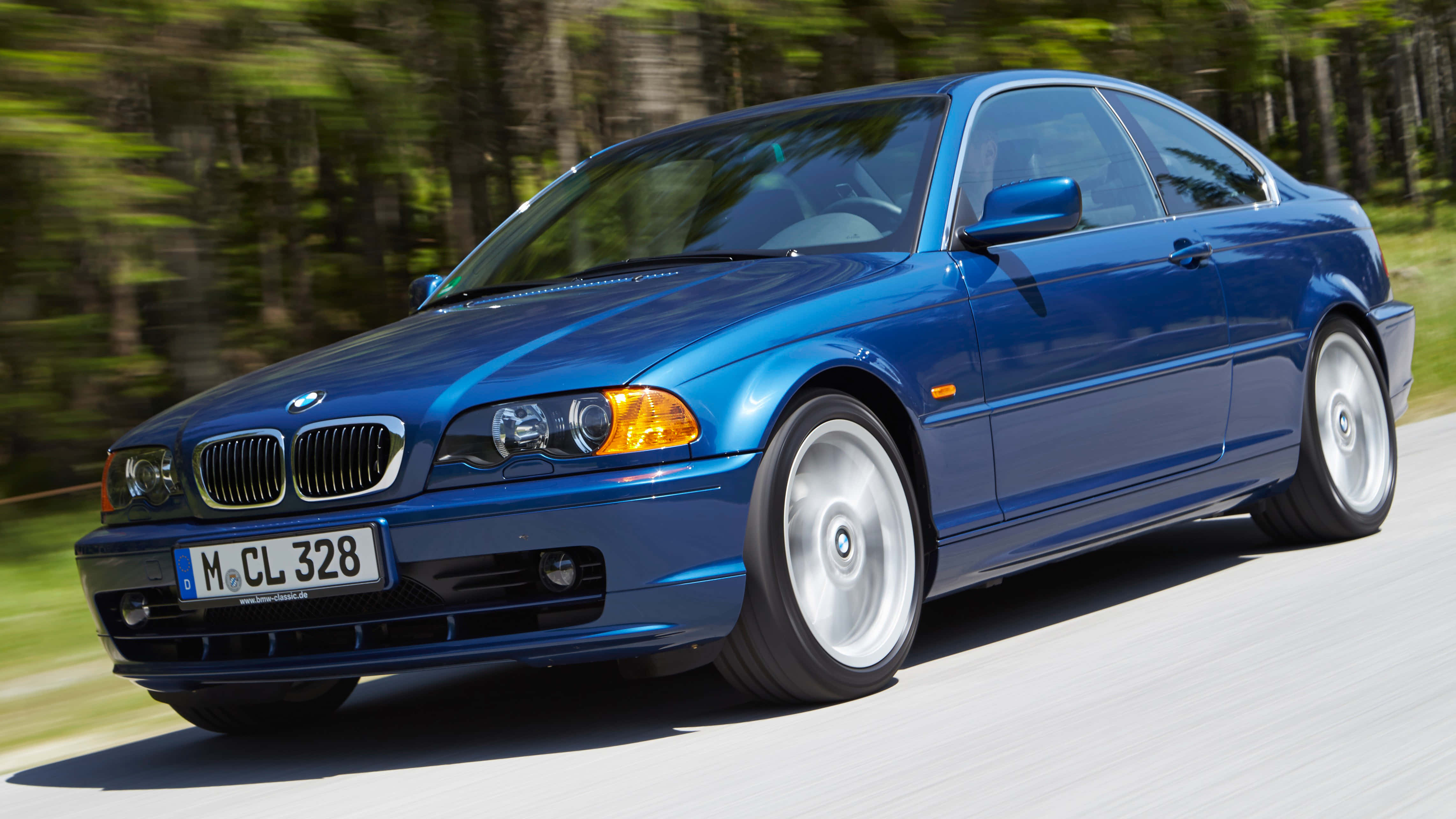 Bmw 3 Series 桌布 壁紙 — 一輛充滿活力的藍色BMW 3系列雙門轎跑車在森林道路上行駛，動態模糊傳達出動感。