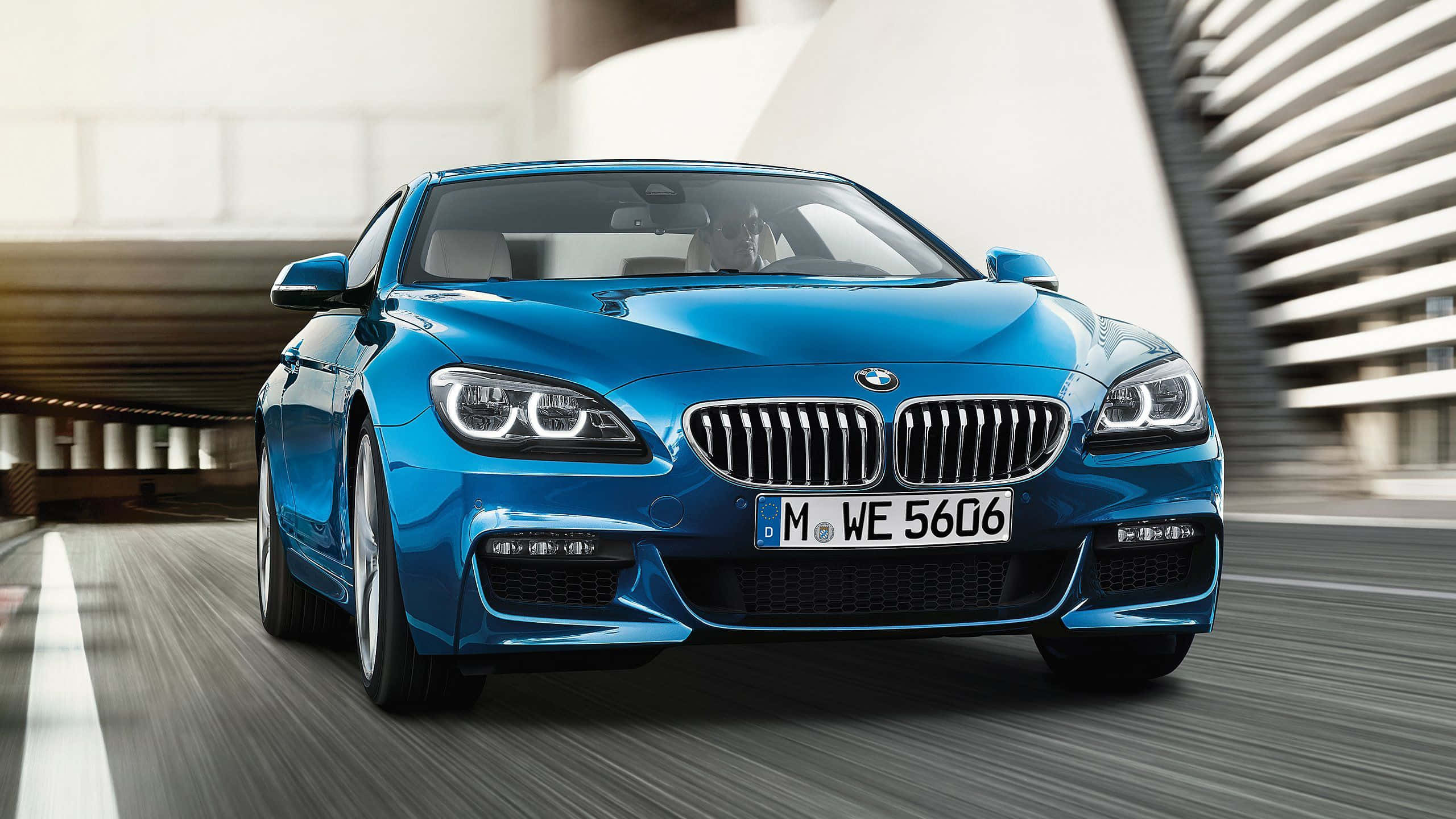 Bmw 6 Series 桌布 壁紙 — 一輛充滿活力的藍色BMW 6系列轎跑車在現代城市道路上疾馳，帶有動態模糊效果和時尚的建築環境。