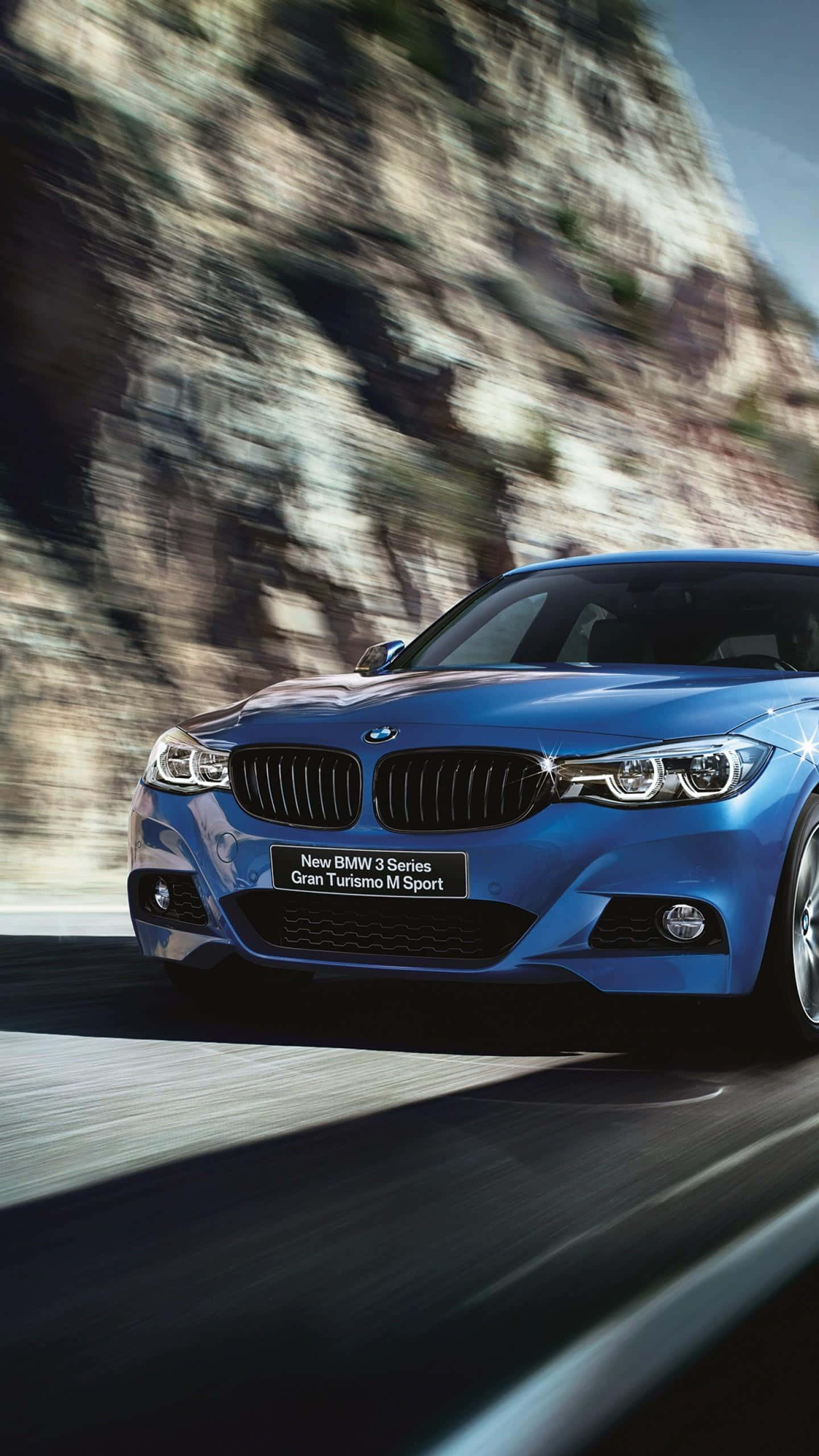 M Series 桌布 壁紙 — 一輛充滿活力的藍色BMW M Sport汽車沿著蜿蜒的山路疾馳，模糊的岩石懸崖飛掠而過。
